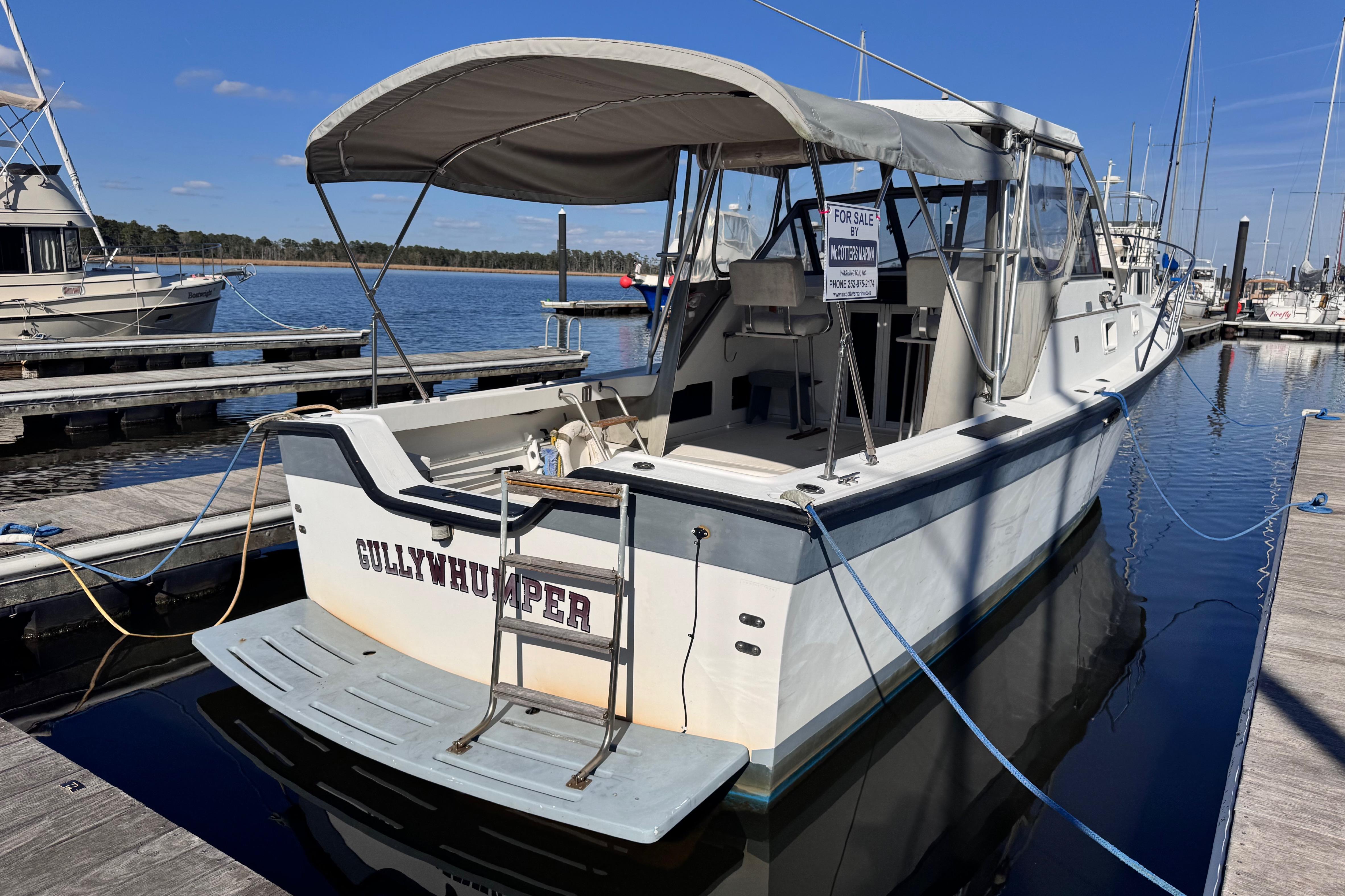 1987 Luhrs Alura 30 boat docked, for sale, with canopy and "Gullywhumper" name.