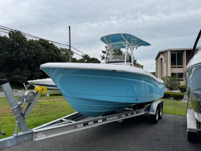 2025 NauticStar 222L Offshore boat on trailer, blue hull, parked outdoors.