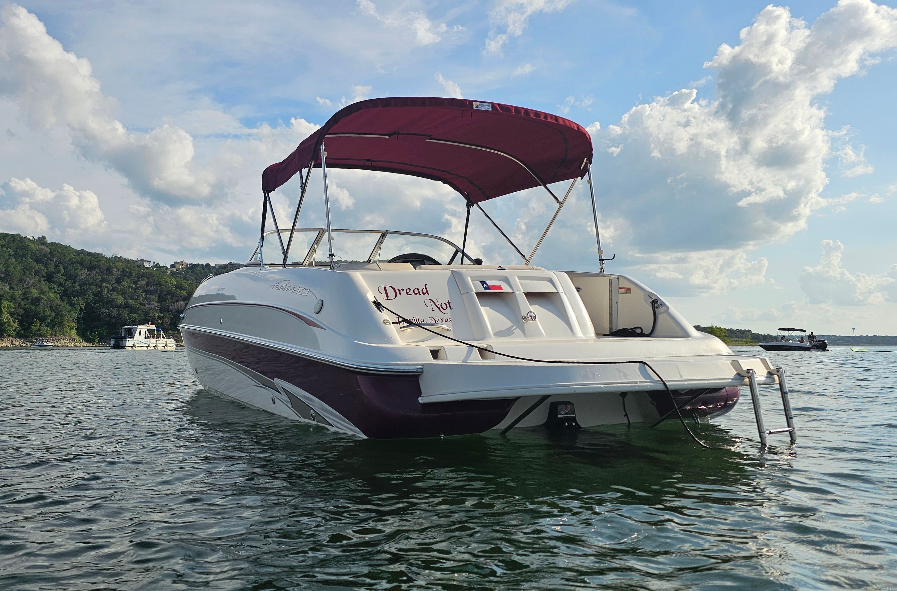 A 2002 Monterey 220 Explorer Sport on the water with a red sunshade.