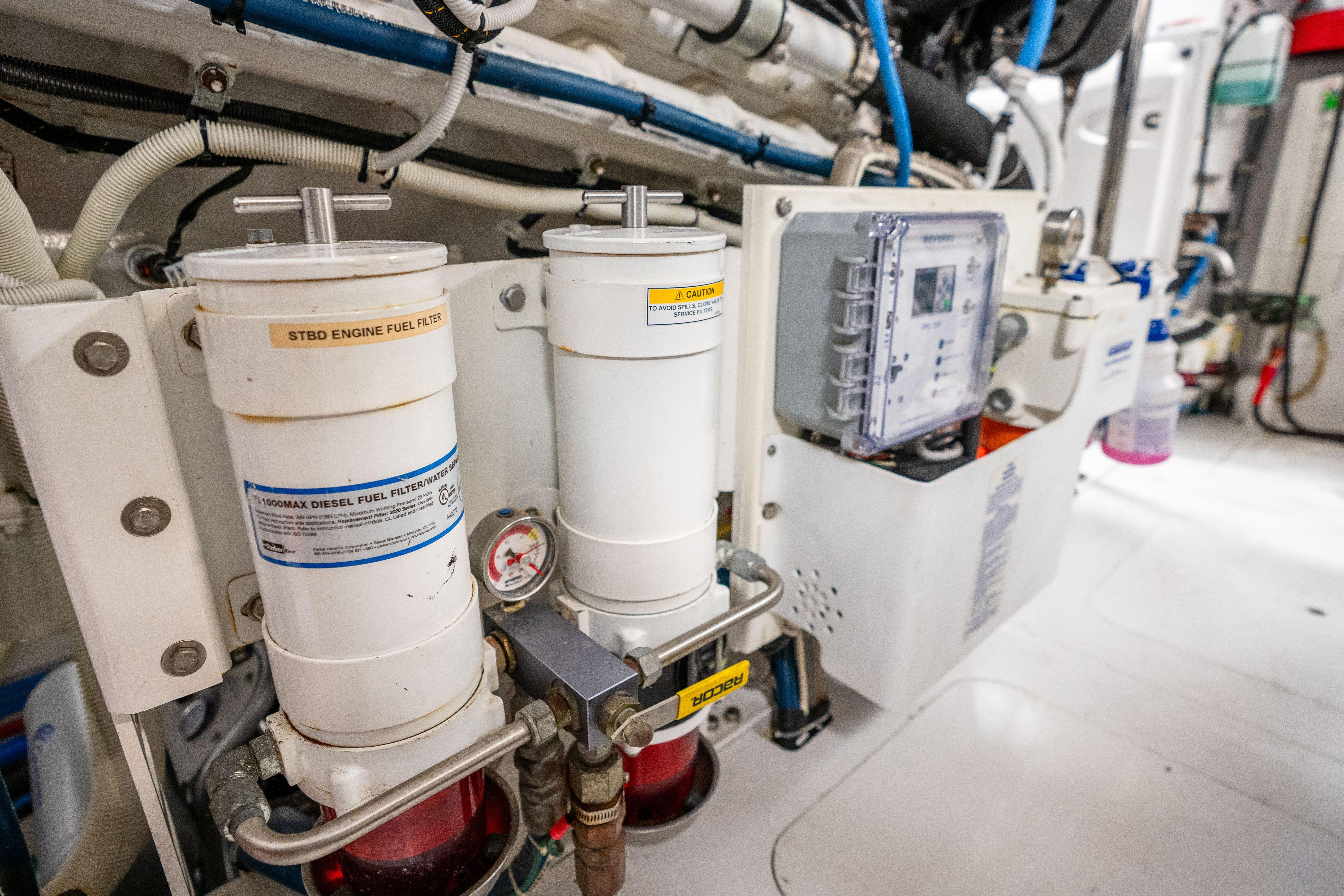 Engine room of 2021 Hatteras M75 Panacera yacht, featuring fuel filters and control panel.