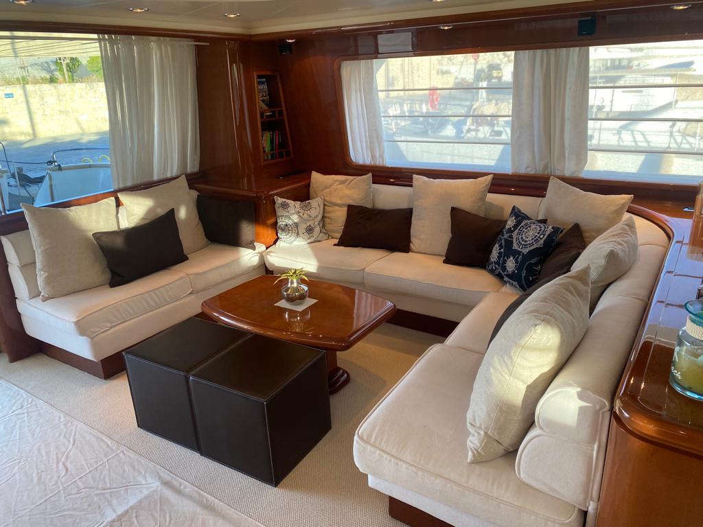 Luxurious yacht interior with cream sofas, dark cushions, and a wooden table, Falcon 86, 2008 model.