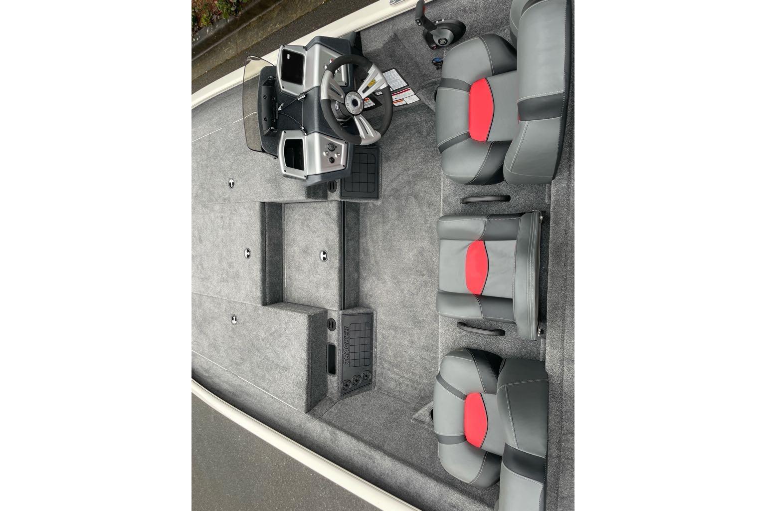 2025 Tracker Savage 215 boat interior with gray and red seating, steering console, and carpeted flooring.