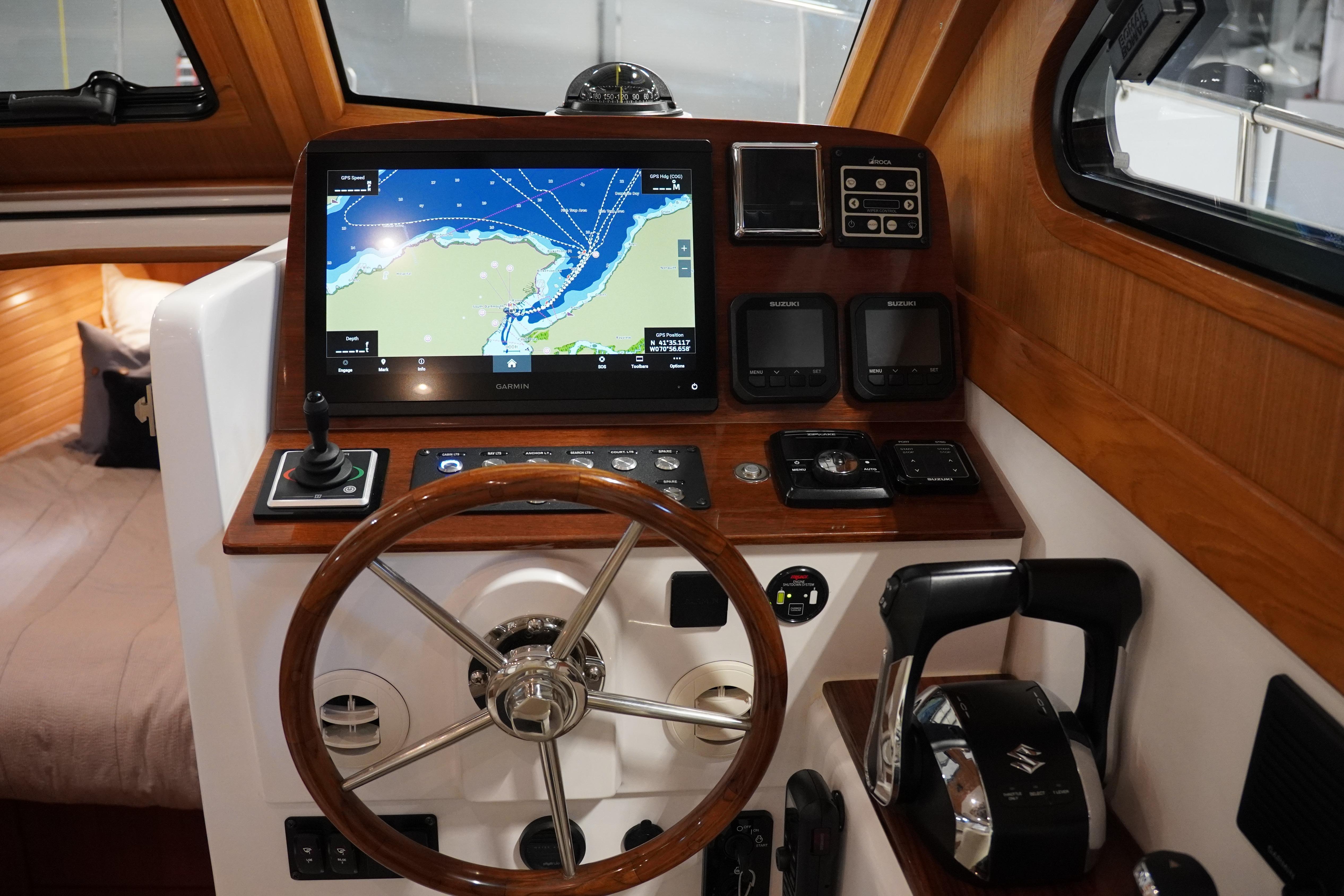2024 True North 34 boat helm with navigation screen and wooden steering wheel.