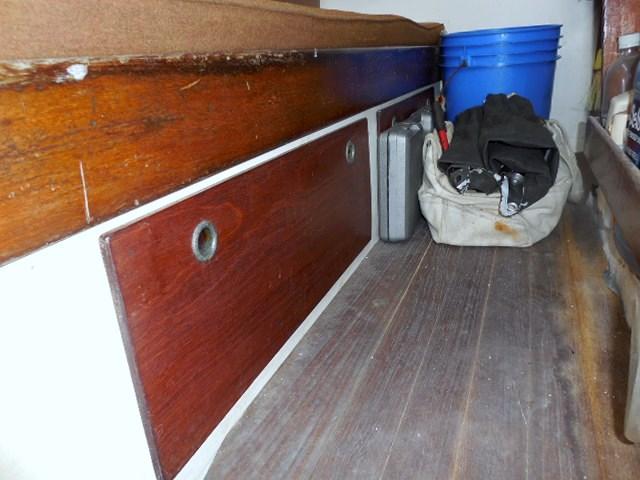 Interior storage area of a 1961 Rhodes Swiftsure boat with wooden paneling and equipment.