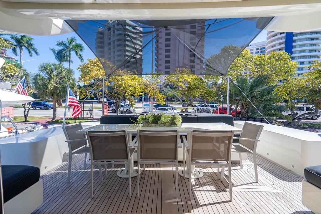 Outdoor dining area on 2007 Arno Leopard 31 yacht, with cityscape and palm trees.