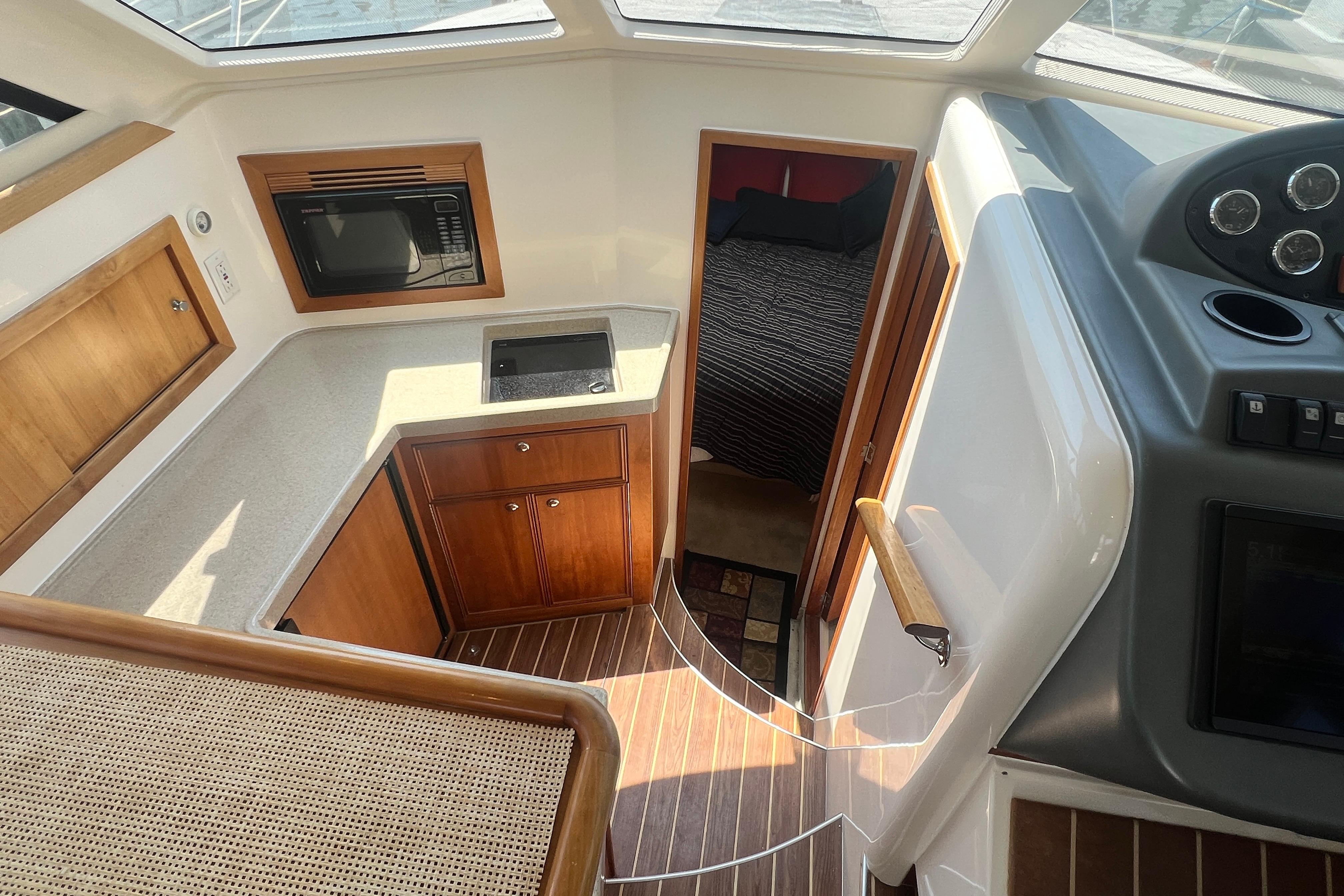 2007 Riviera 33 Flybridge interior with kitchenette, microwave, and cozy cabin view.