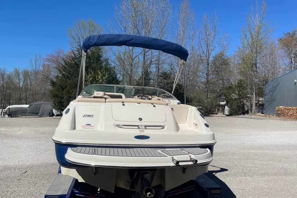 2007 Chaparral 215 SSi boat with blue canopy, parked outdoors on a sunny day.