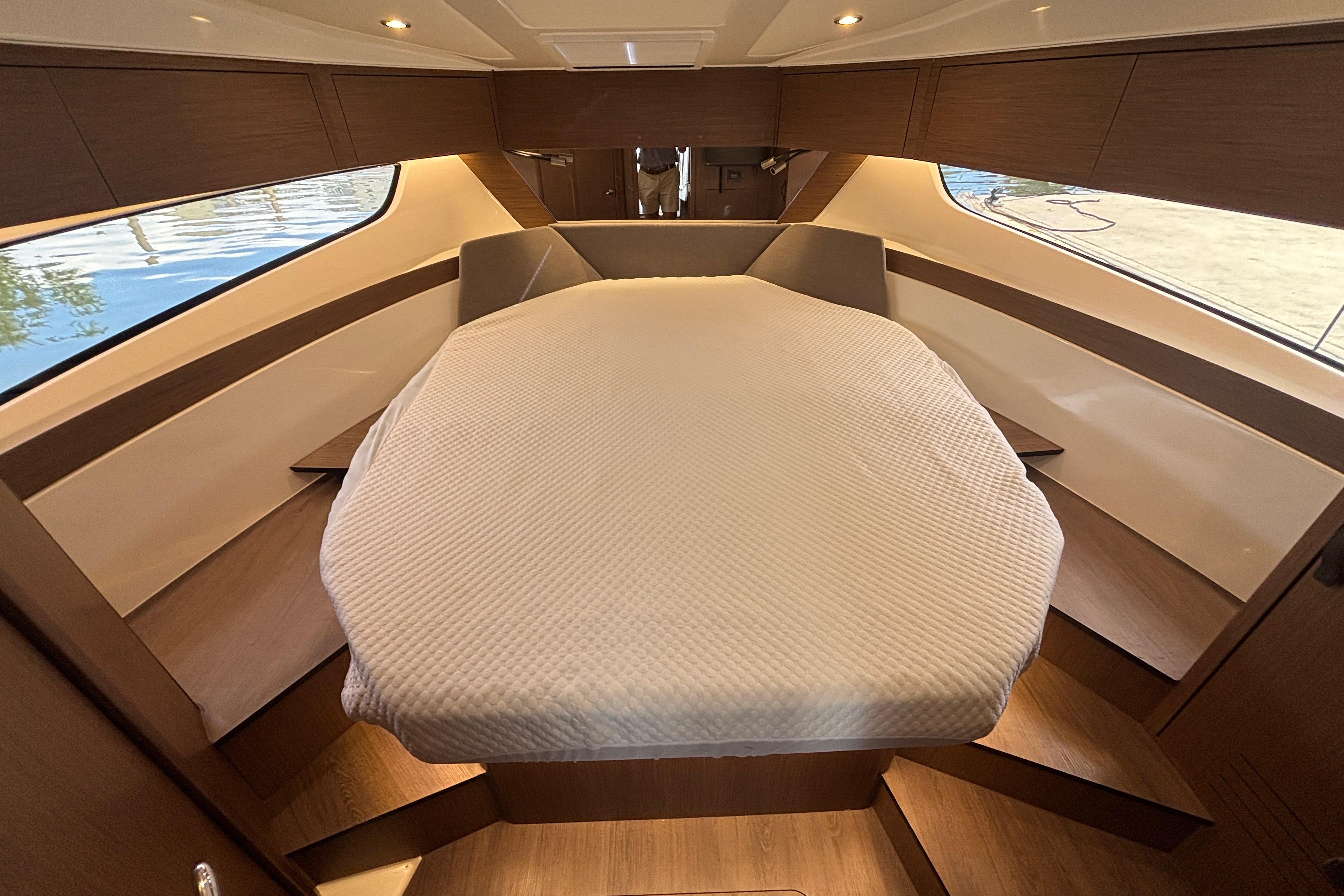 Luxurious cabin interior of 2024 Beneteau Antares 11 with cozy bed and elegant wood finish.
