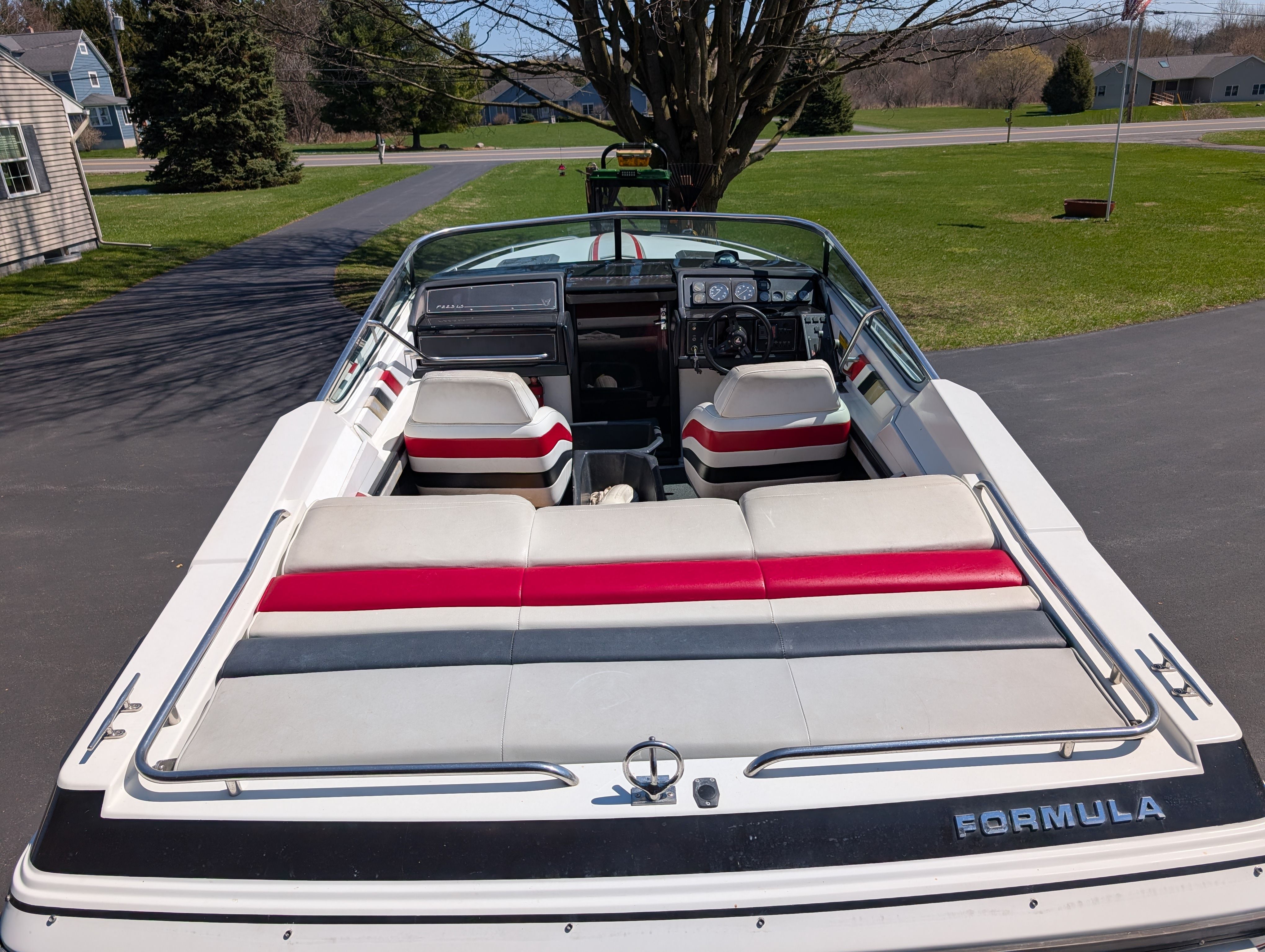 The image shows a white boat with red and gray accents parked on a driveway.