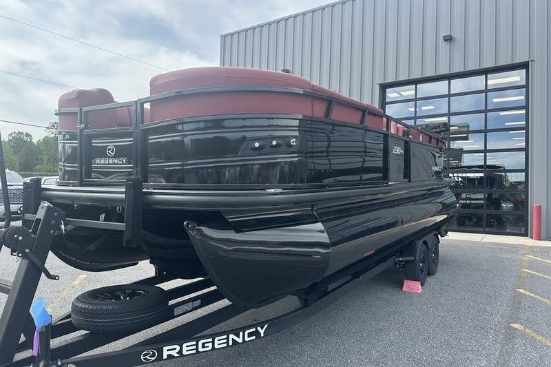 2026 Regency 230 DL pontoon boat on trailer outside a modern building.