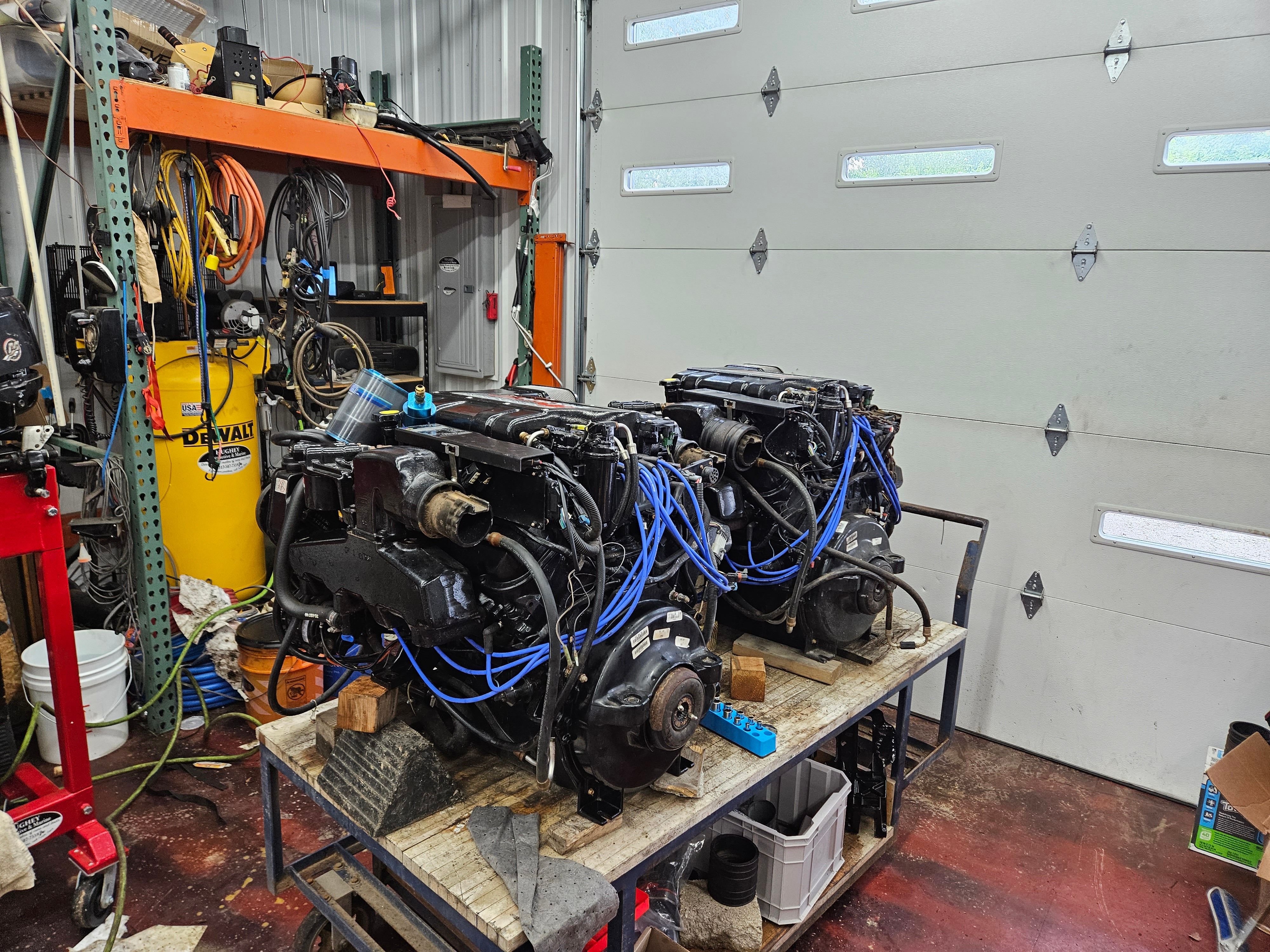 Two engines on a table in a workshop with tools and equipment in the background.