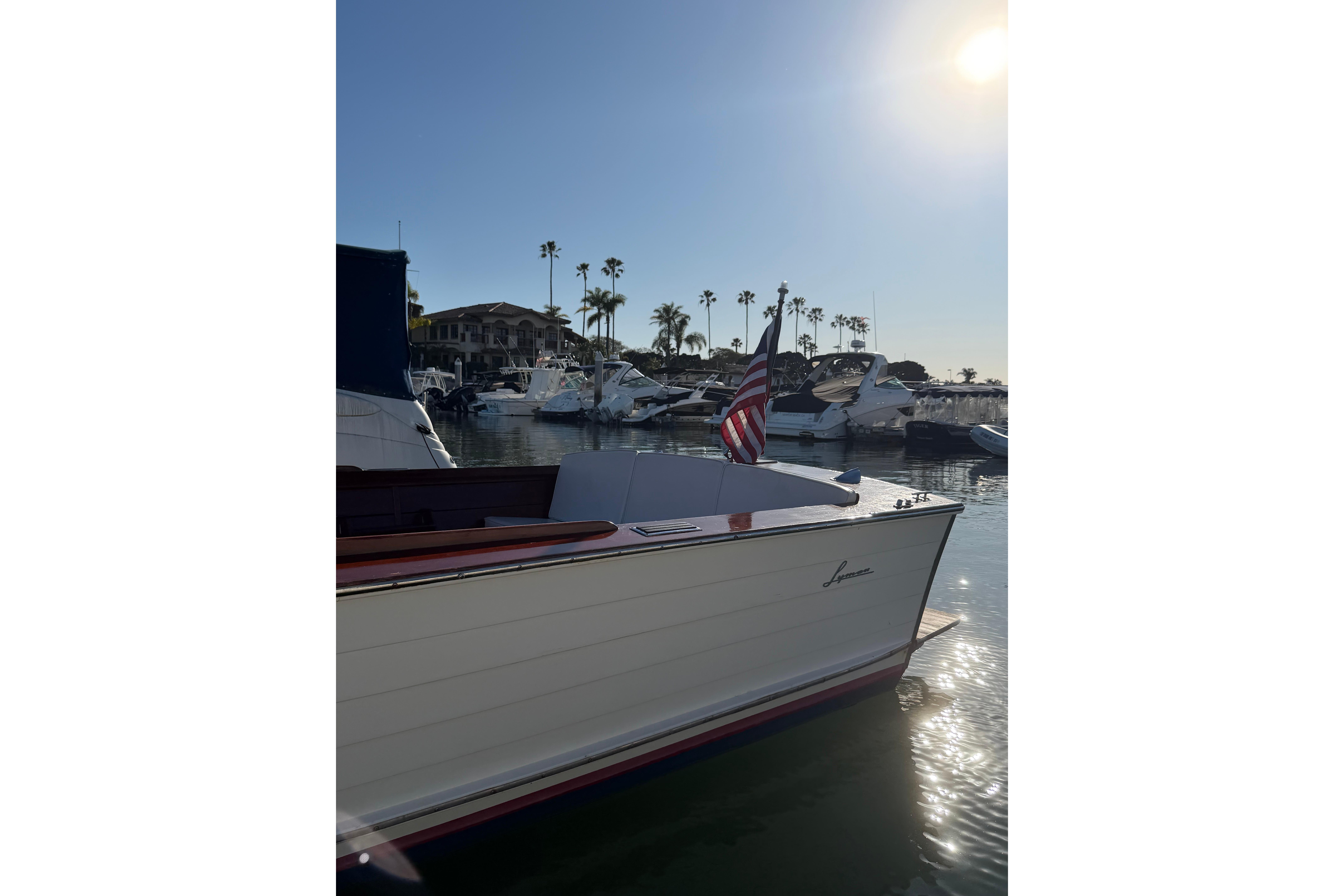 1964 Lyman 25 Sleeper boat docked in sunny marina with American flag.
