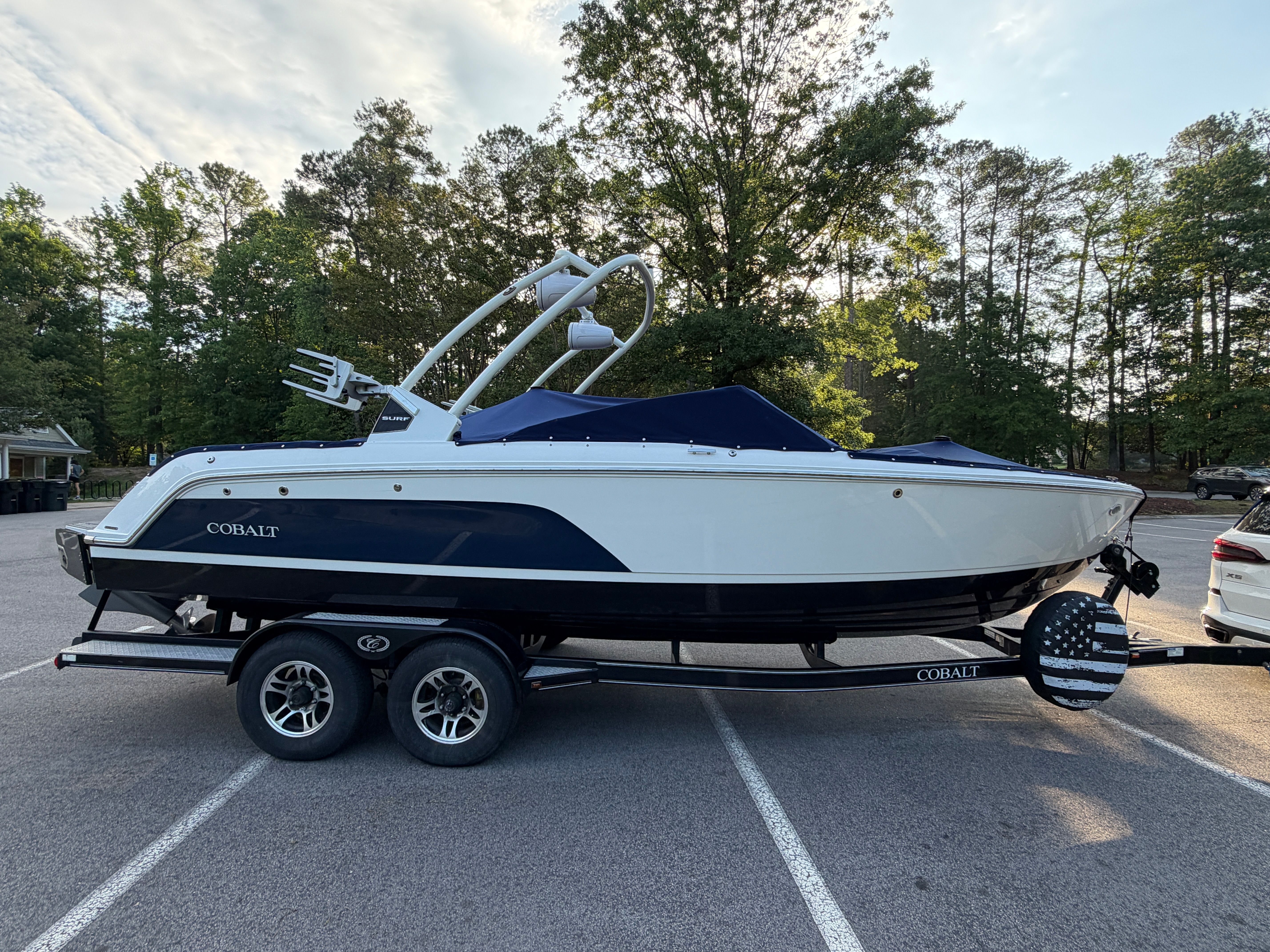 A 2024 Cobalt CS23 Surf boat is on a trailer in a parking lot.