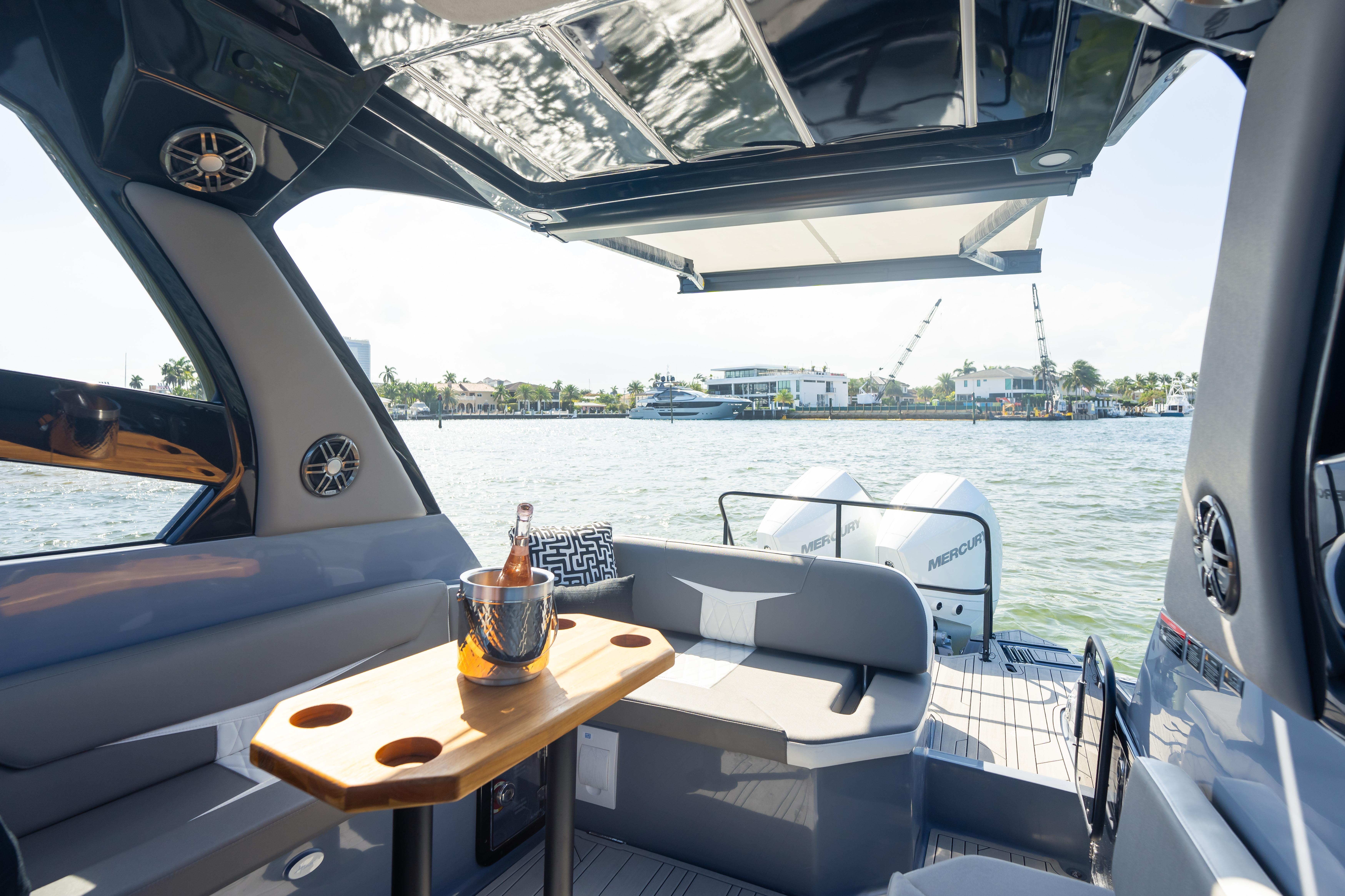 Luxurious Hanover 305 boat interior with seating, table, and scenic waterfront view, 2026 model.