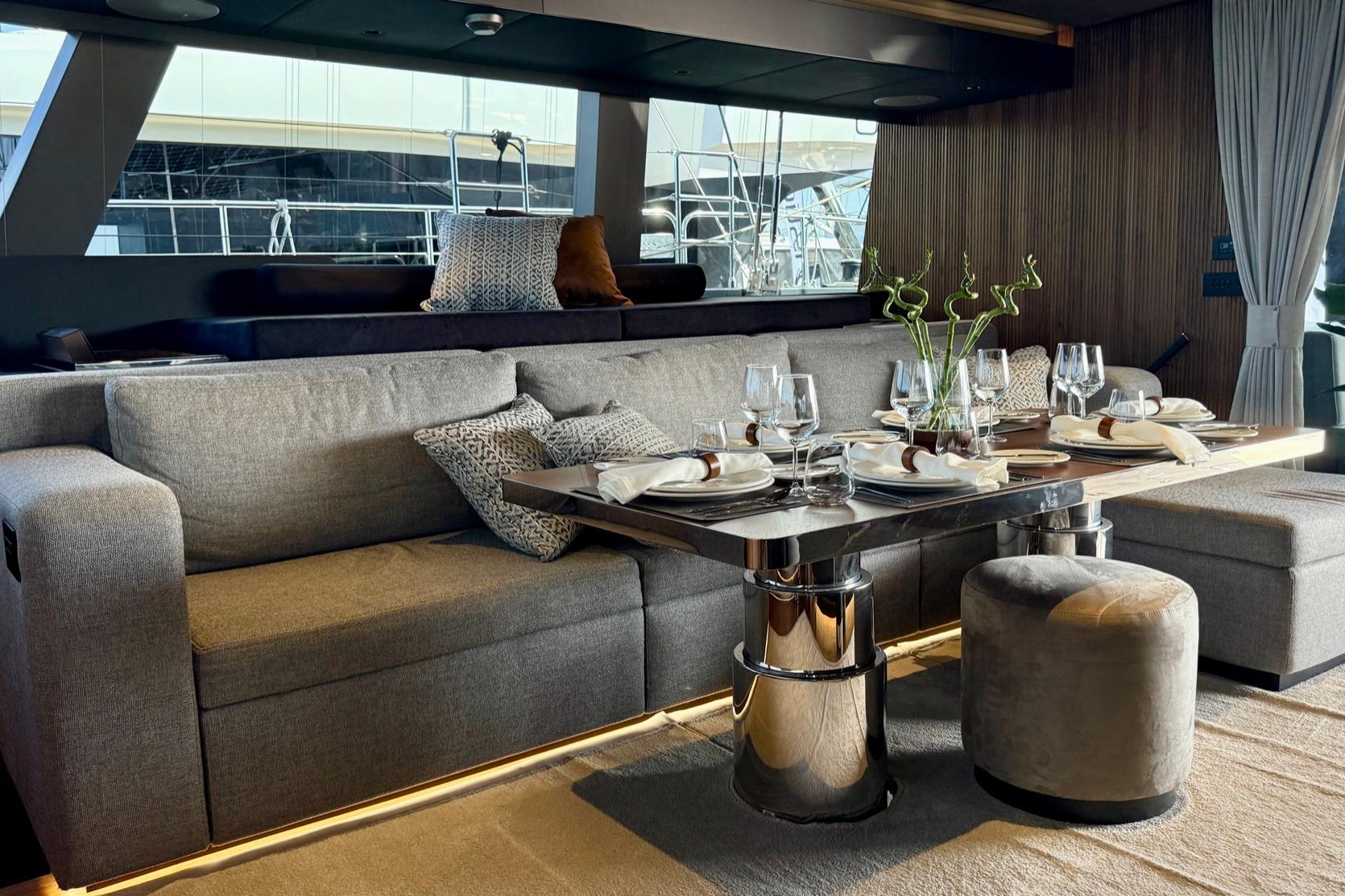 Luxurious interior of 2024 Sunreef 60 yacht with elegant dining setup and plush seating.