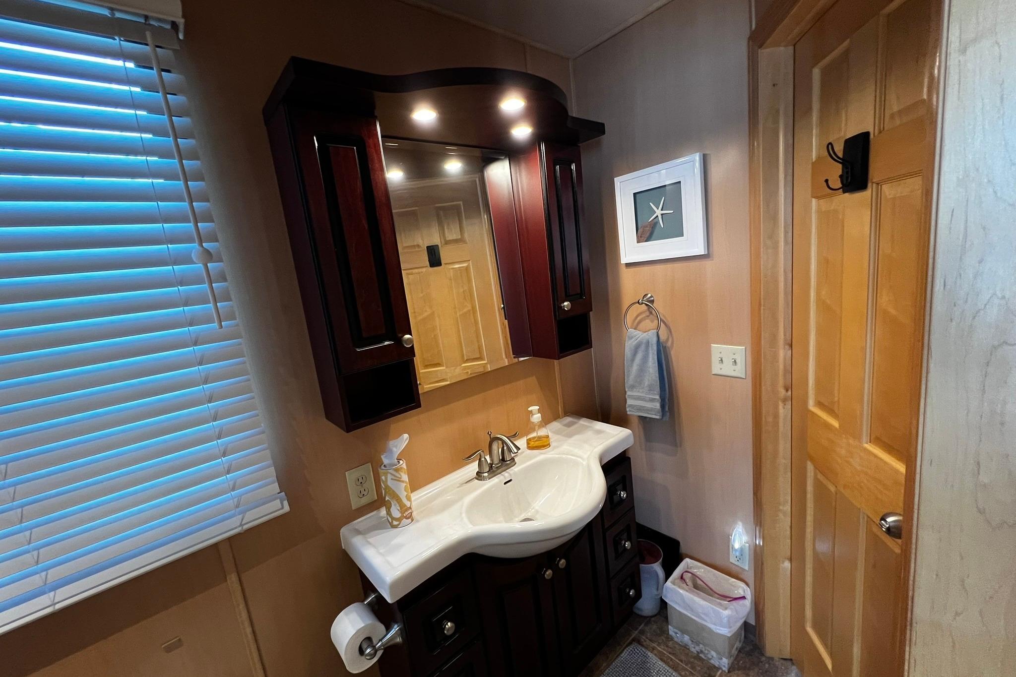 Bathroom vanity area on a 2010 Skipperliner 480 Flybridge with wooden cabinets and mirror.