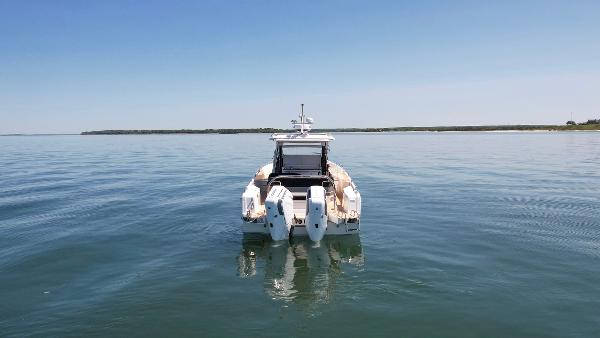 2025 Nimbus T11 boat on calm water, rear view with clear sky.