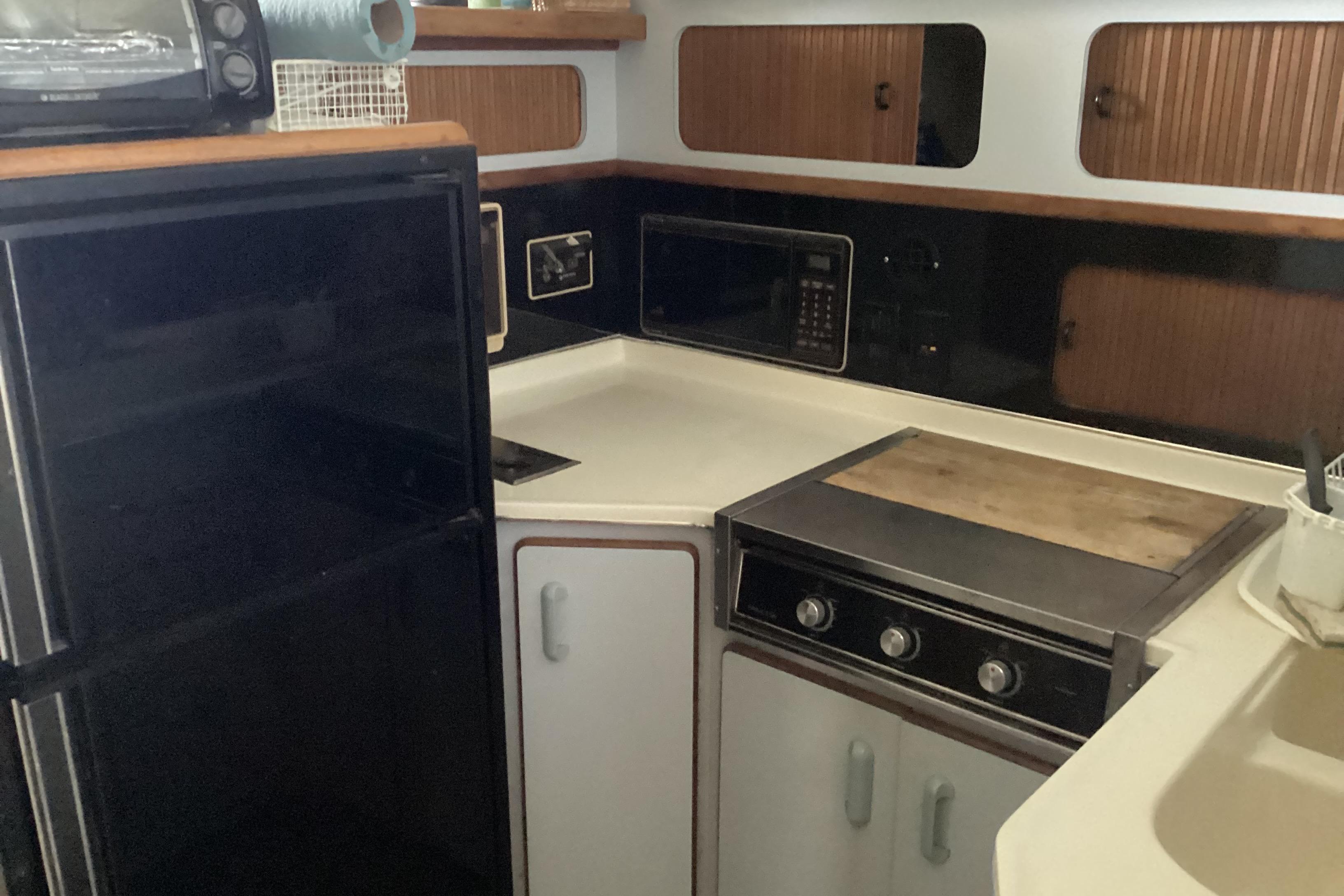 1989 Sea Ray 380 Aft Cabin kitchen with stove, microwave, and refrigerator.