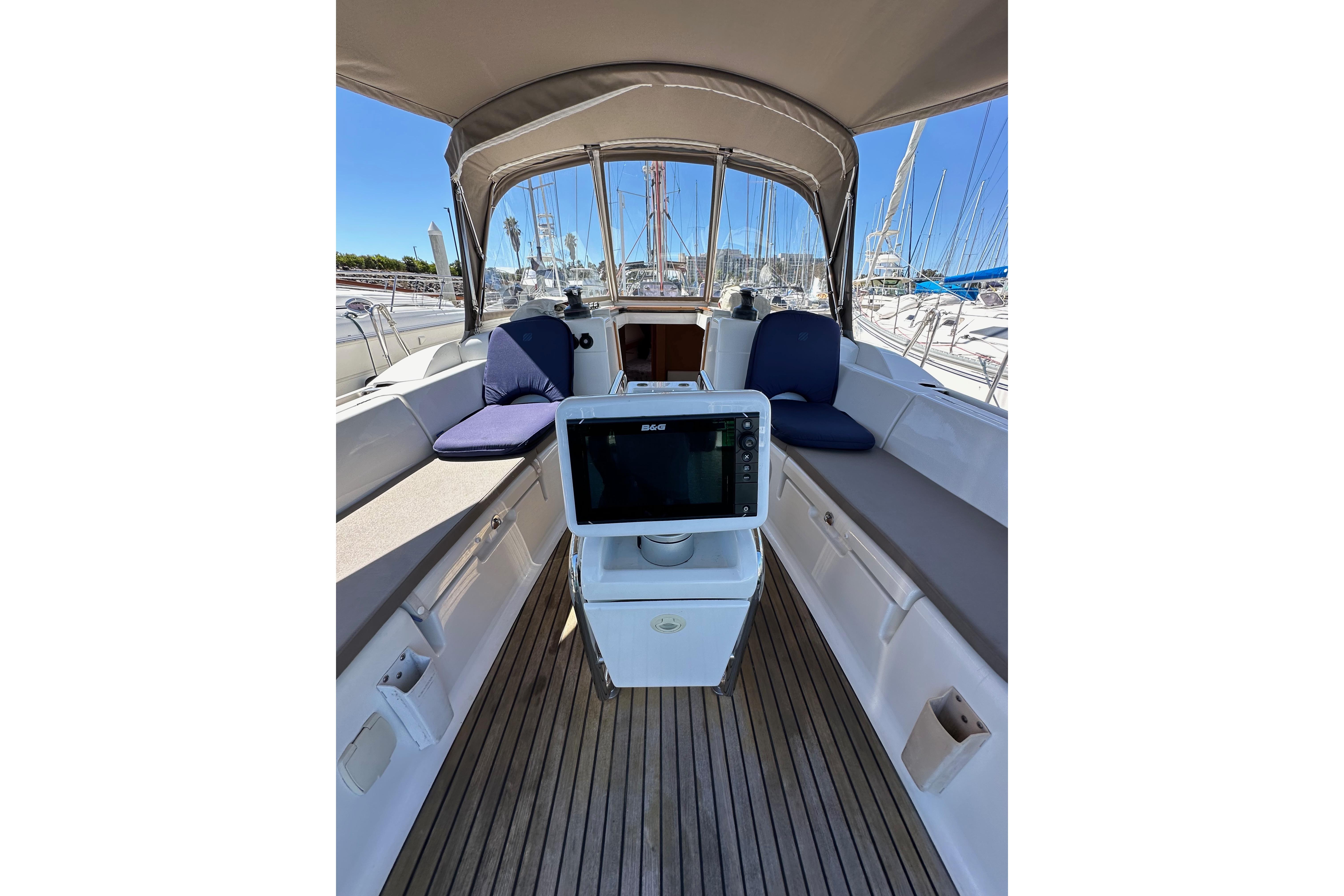 2015 Jeanneau Sun Odyssey 409 cockpit with seating, navigation equipment, and marina view.