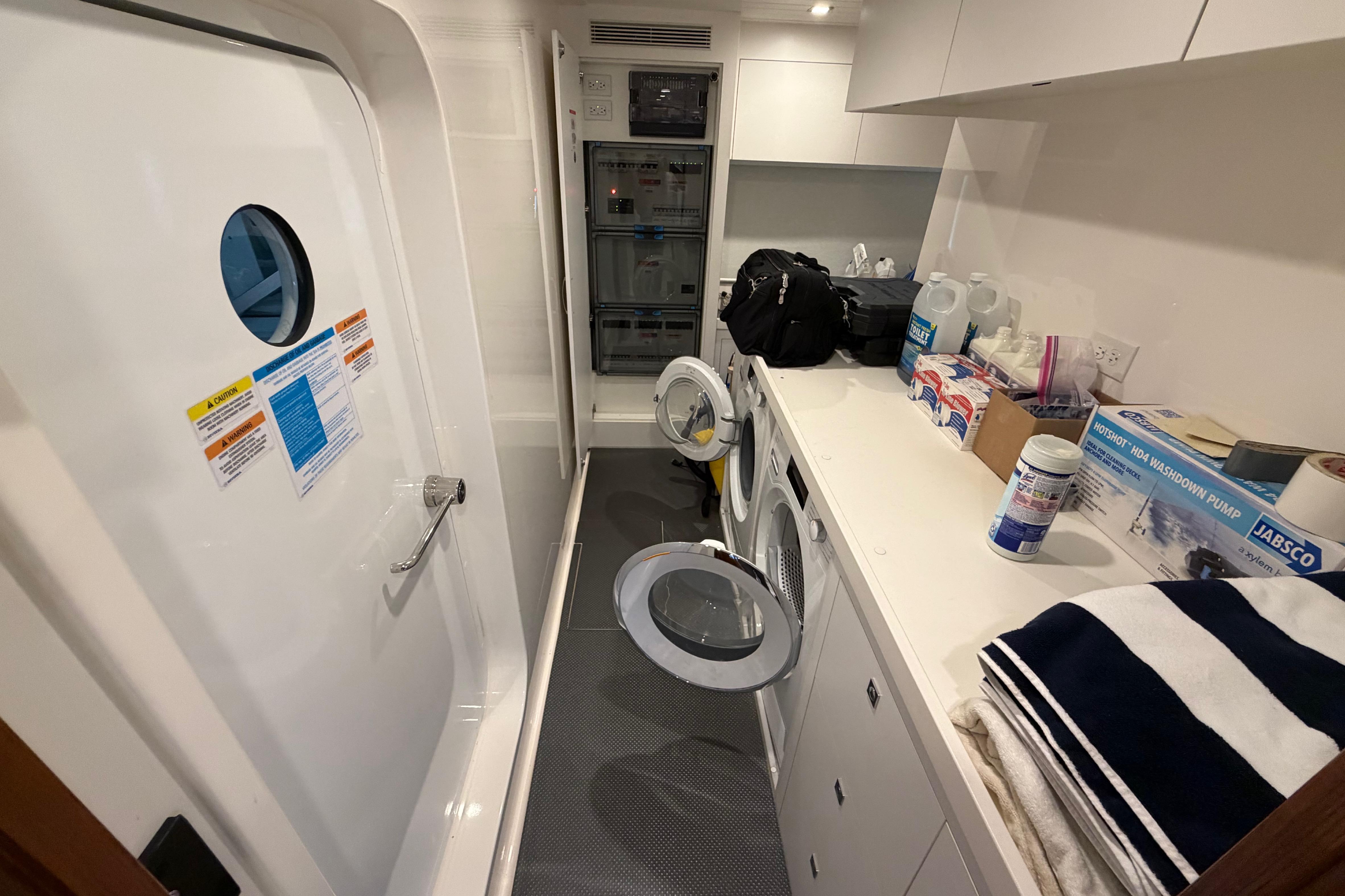 Laundry room inside 2023 Riviera 645 SUV yacht, featuring washer, dryer, and storage.