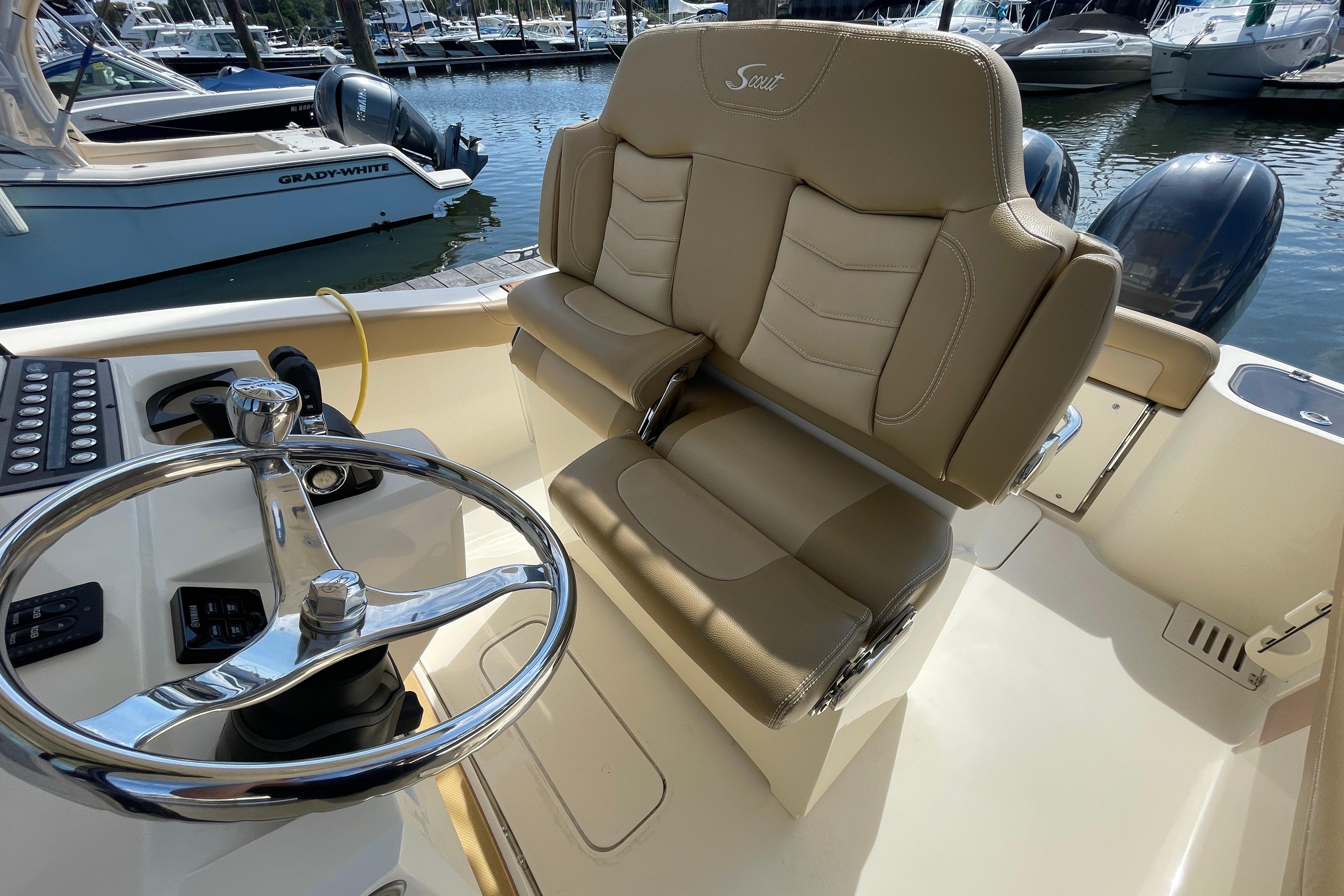 2020 Scout 255 LXF boat interior with steering wheel and beige seating at marina.