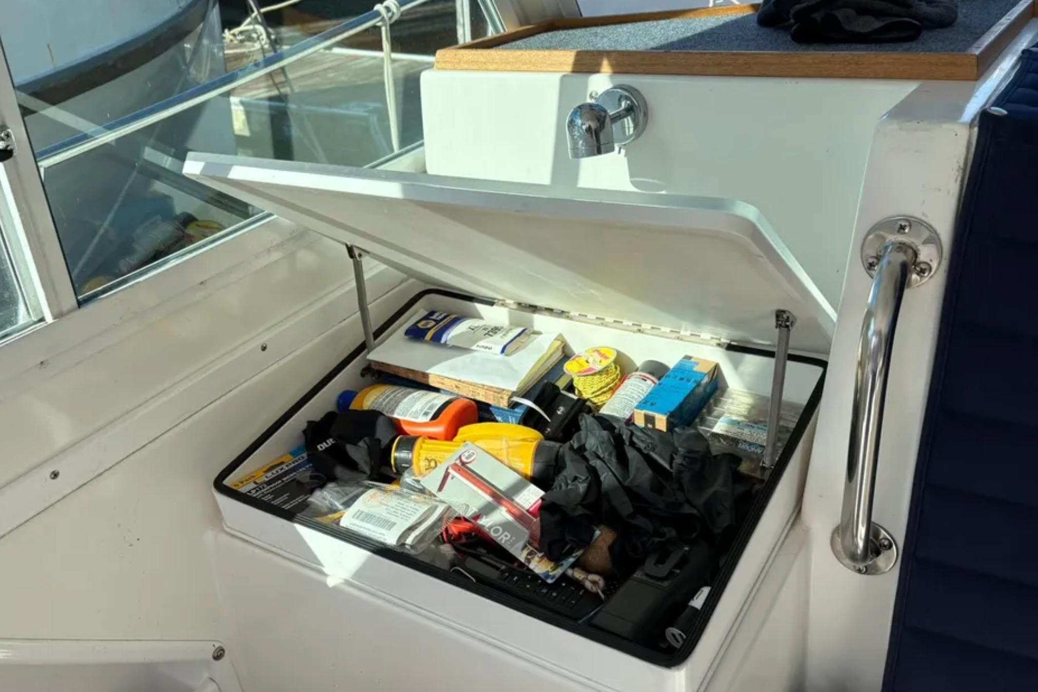 Open storage compartment on 2005 Albin 28 Tournament Express boat, containing various supplies.