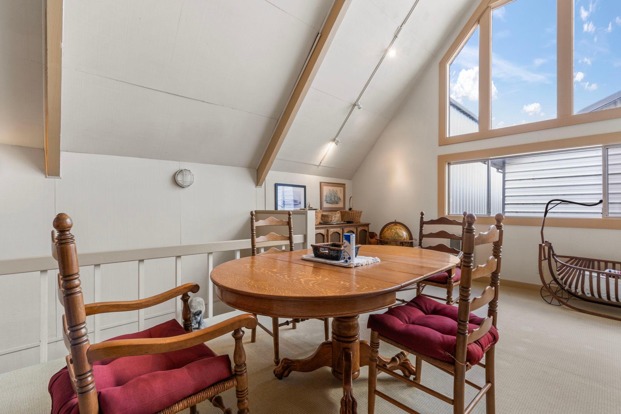 Cozy boathouse interior with wooden dining table, chairs, and large windows, built in 1976.