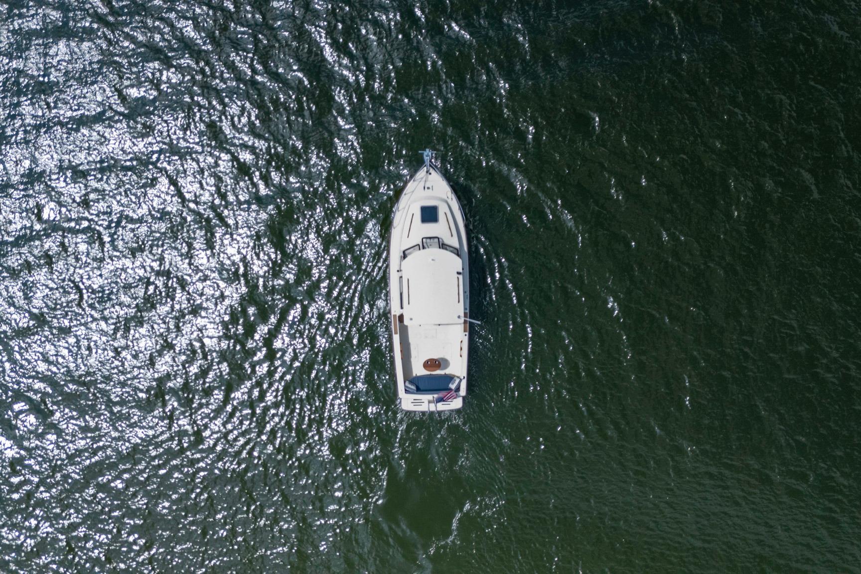 Aerial view of 2006 Atlas Boat Works Acadia 25 cruising on shimmering water.