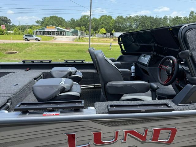 The image shows the cockpit of a 2025 Lund 2075 Impact XS boat with two seats and a steering wheel.
