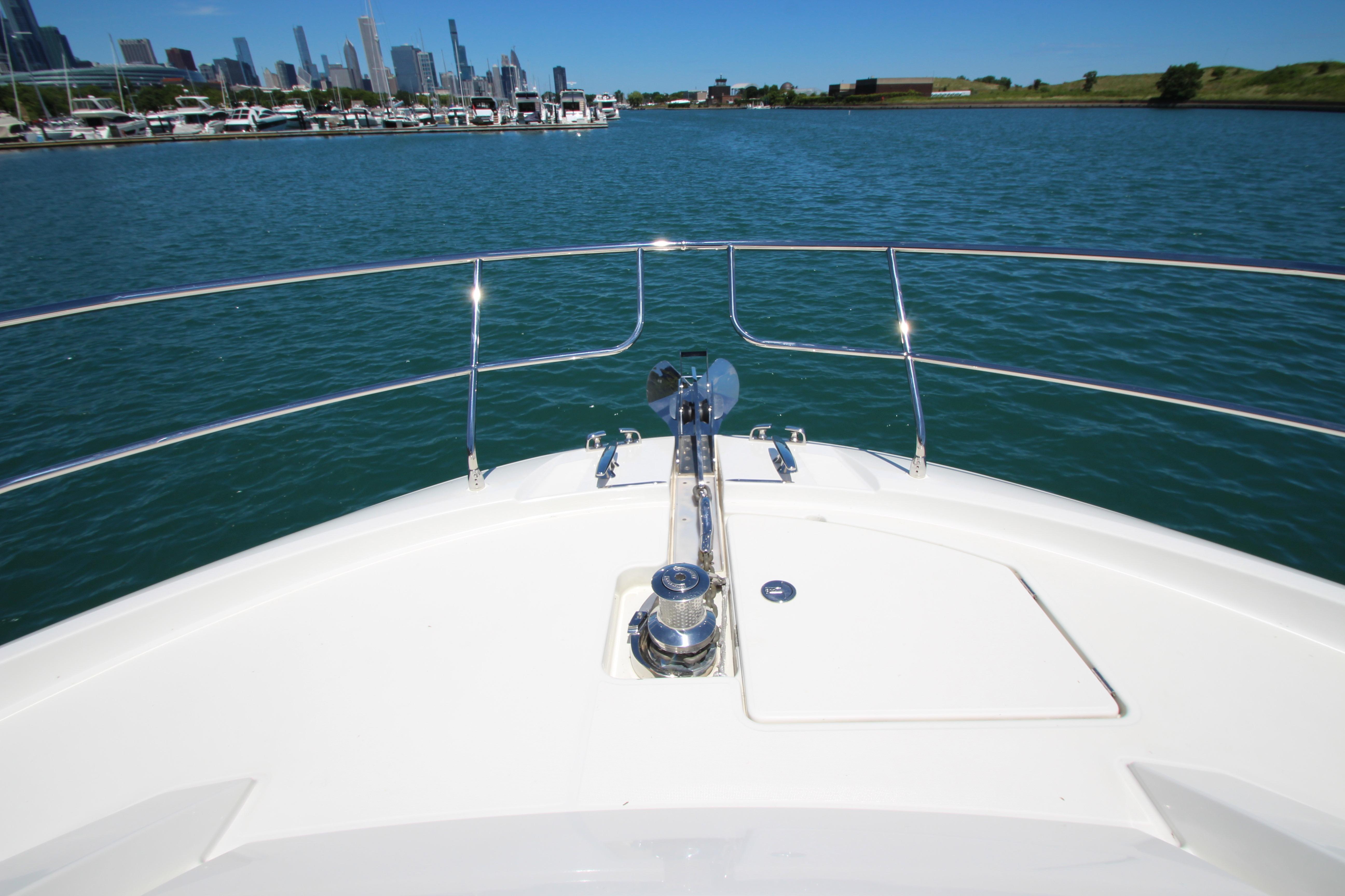 Bow view of 2022 Prestige 520 yacht on a sunny day, city skyline in background.
