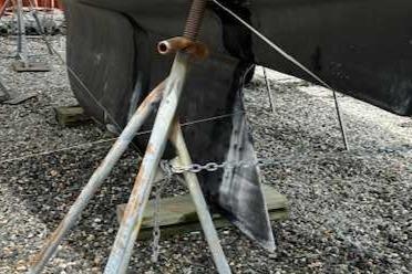 1969 Contest 29 sailboat hull supported by metal stands on gravel.