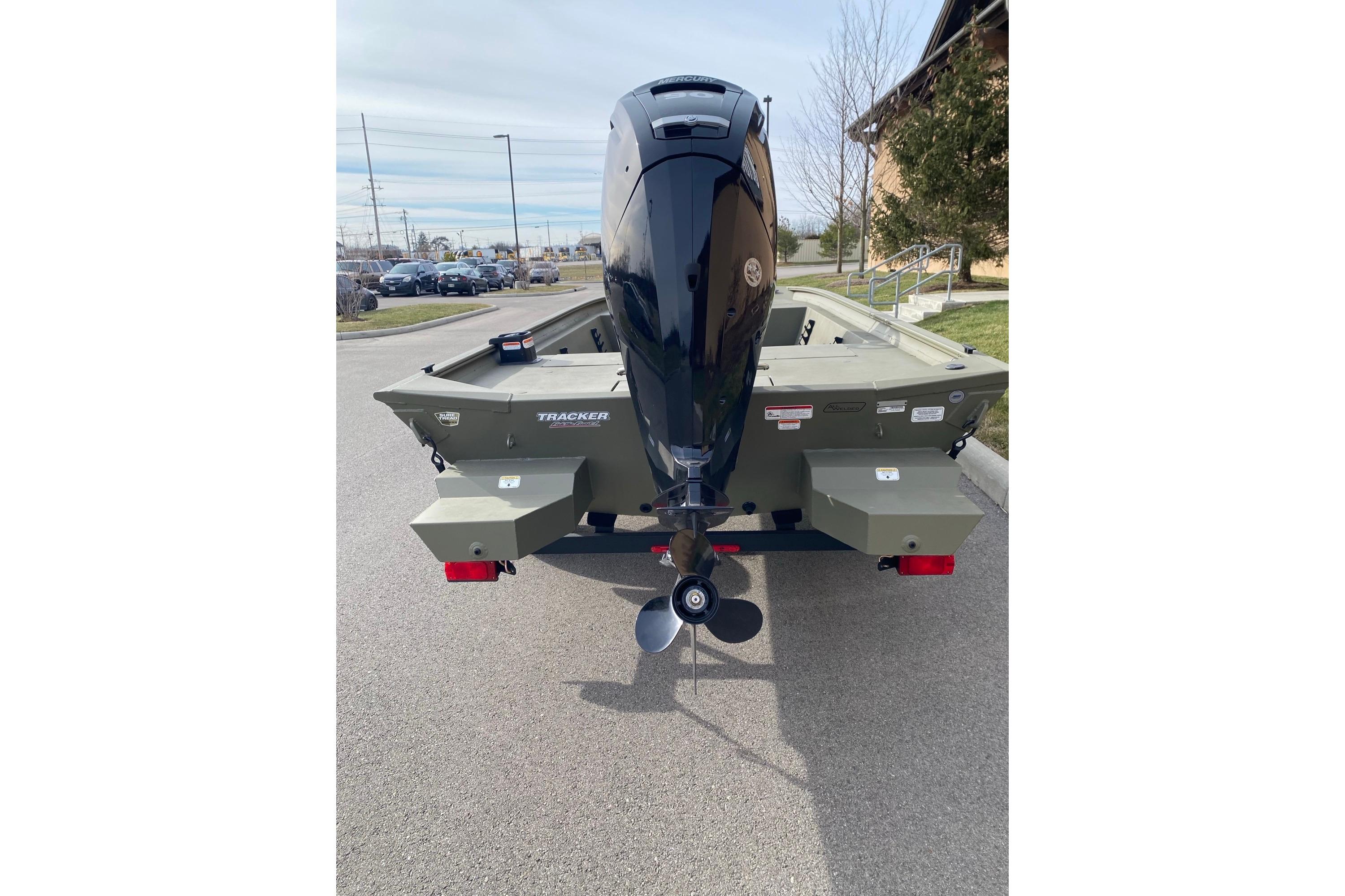 2026 Tracker Grizzly 1860 CC boat with outboard motor, parked on pavement.