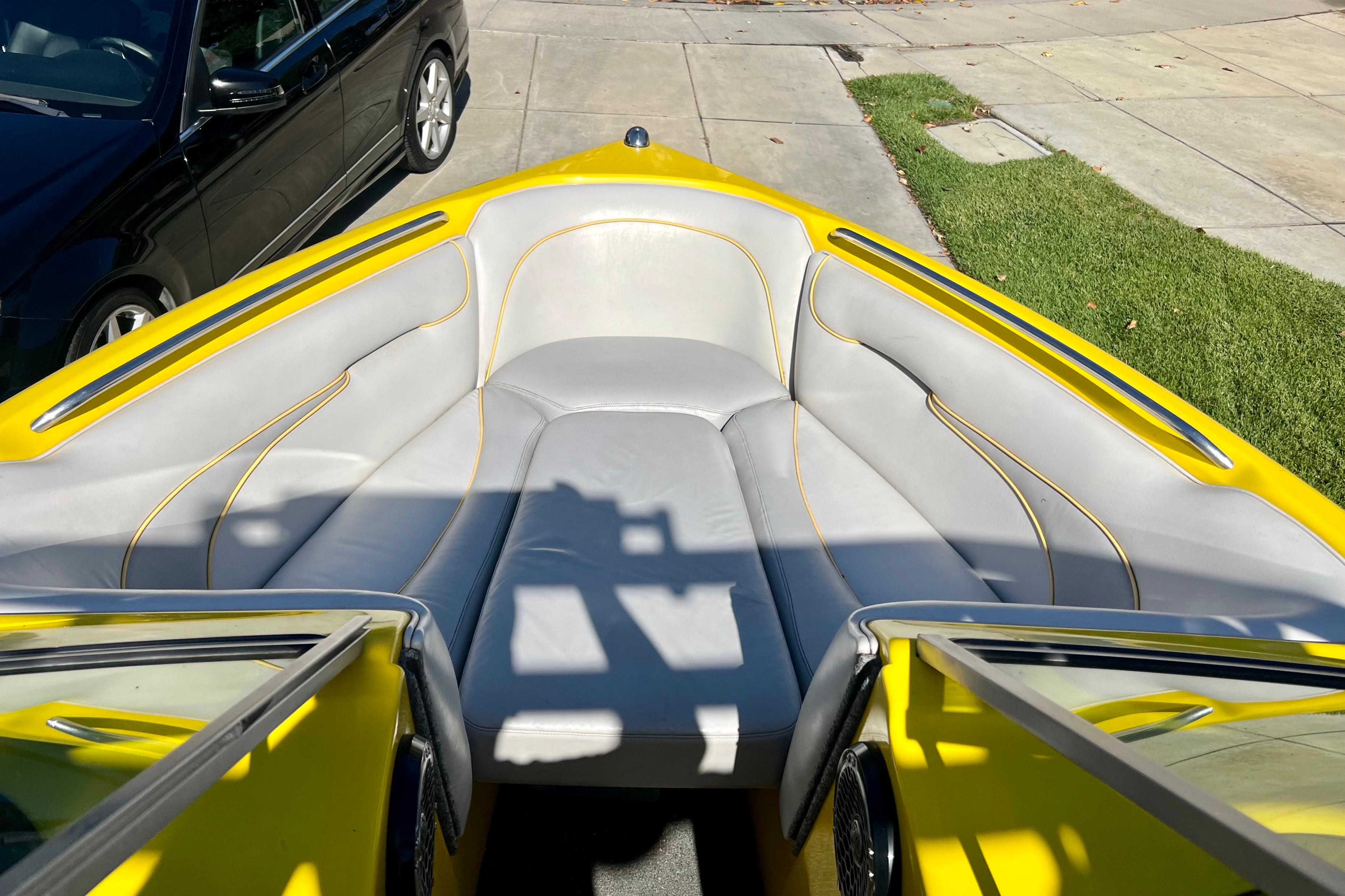 Yellow 2006 Sanger V230 boat interior with gray seating, parked on driveway.