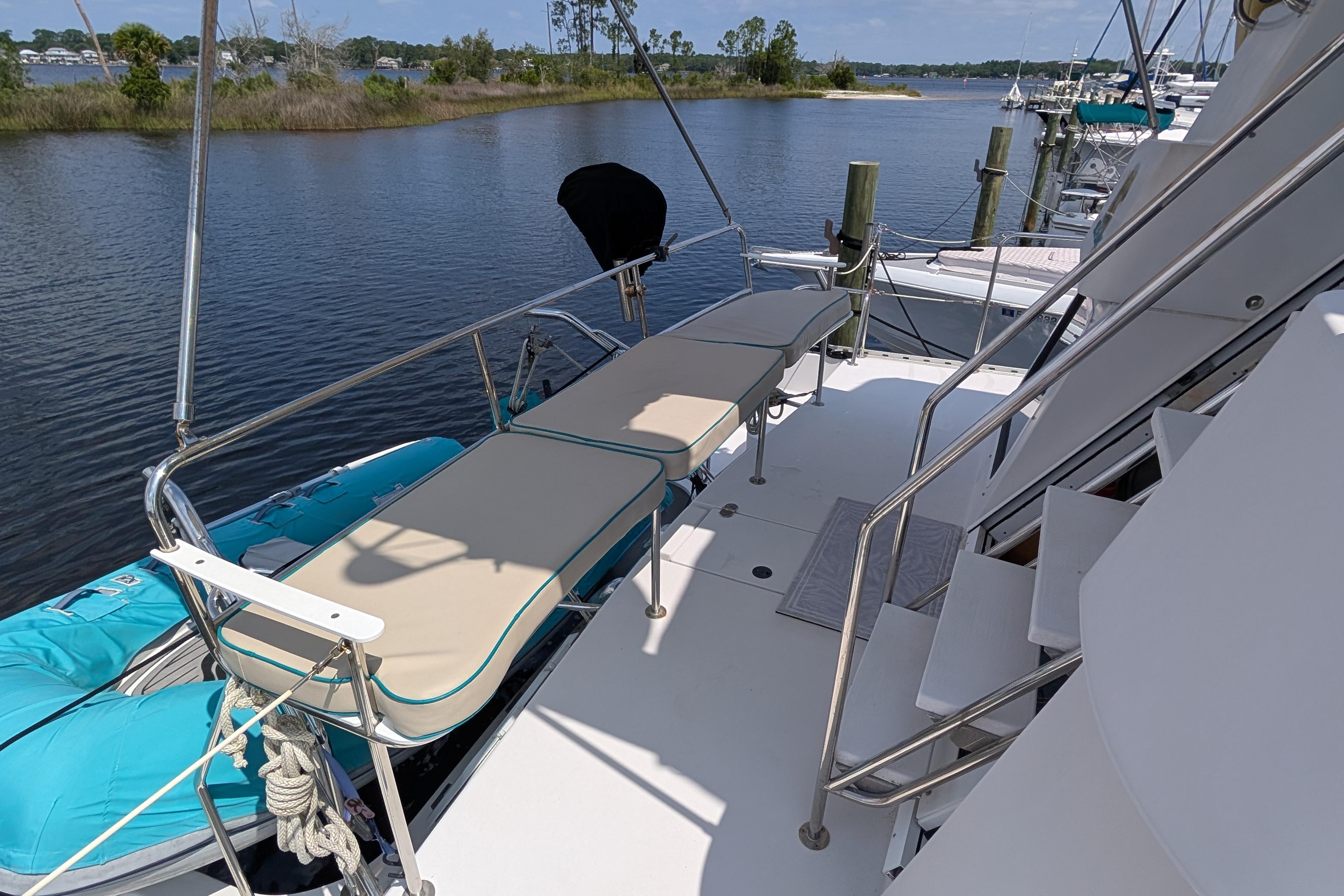 2004 PDQ 34 Powercat boat deck with seating, docked by a serene waterfront.