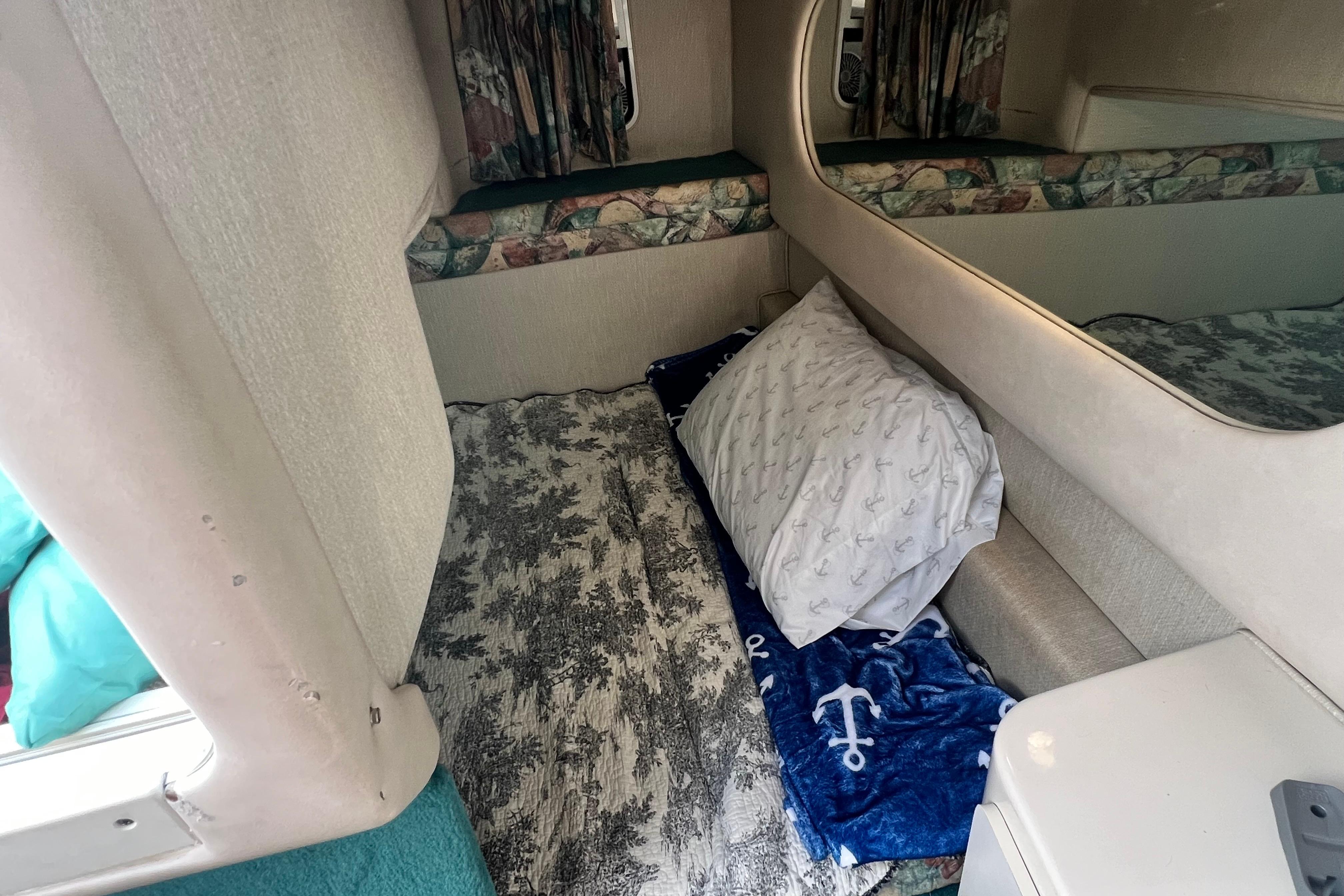 1997 Sea Ray 270 Sundancer cabin interior with bedding and nautical-themed decor.