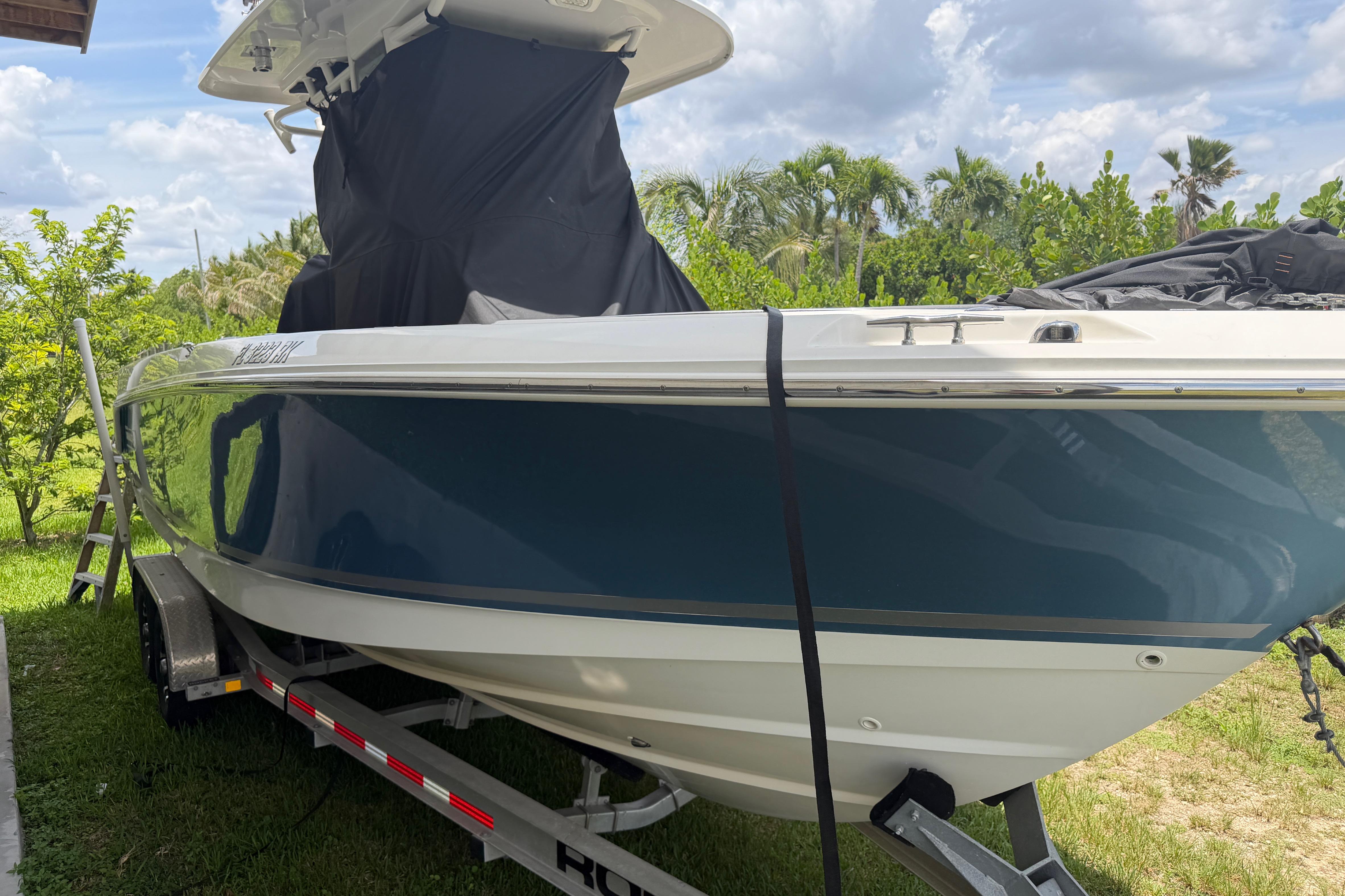 2016 Boston Whaler 250 Outrage boat on trailer, surrounded by lush greenery.