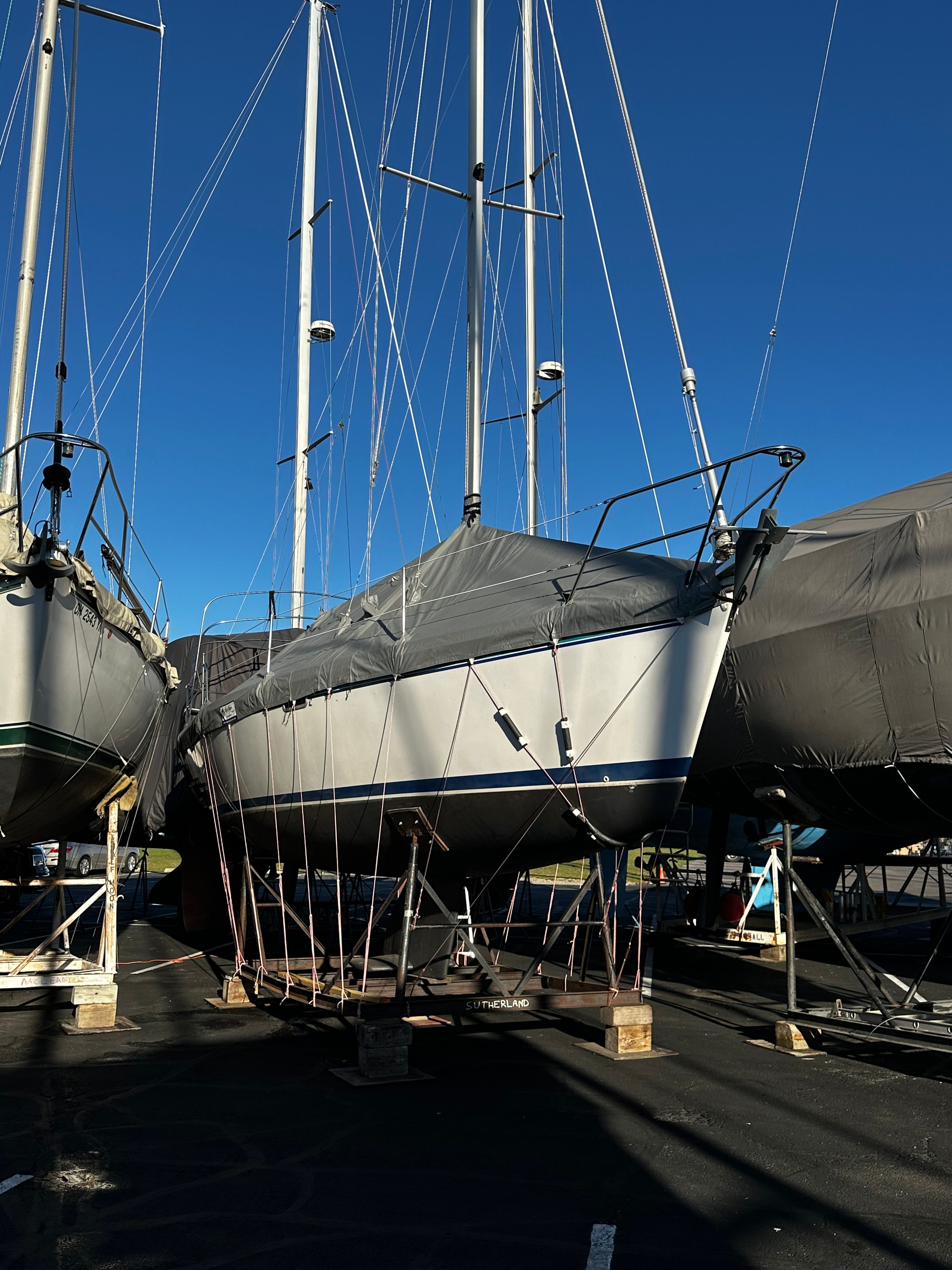 A 1995 Catalina 320 sailboat is on a dry dock, surrounded by other boats.