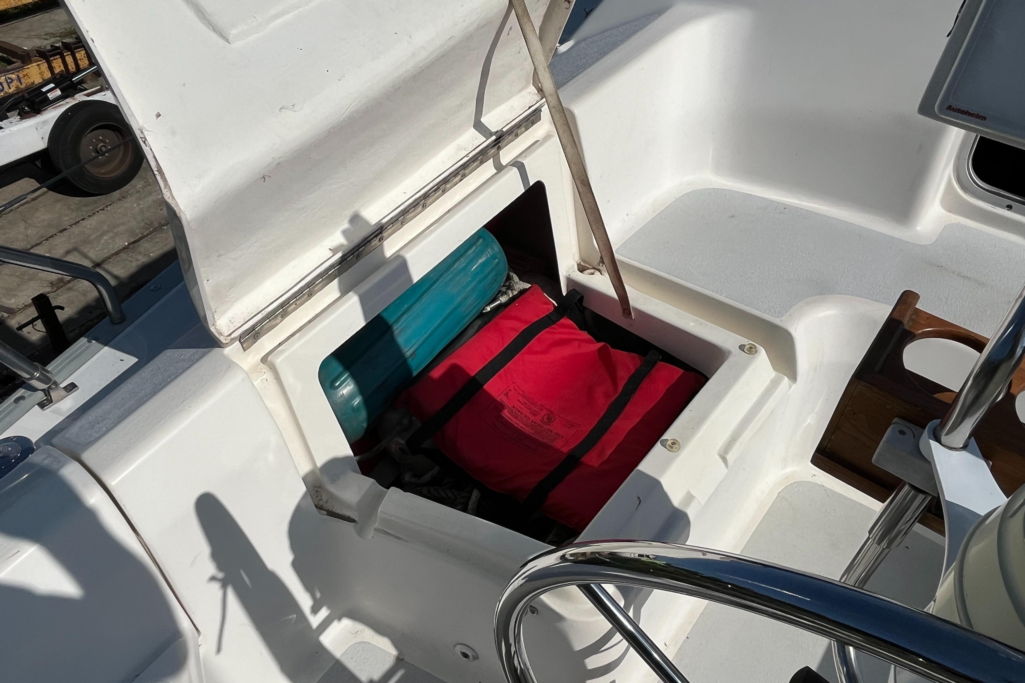 Open storage compartment on 1992 Hunter 30-2 sailboat, revealing red and teal items inside.