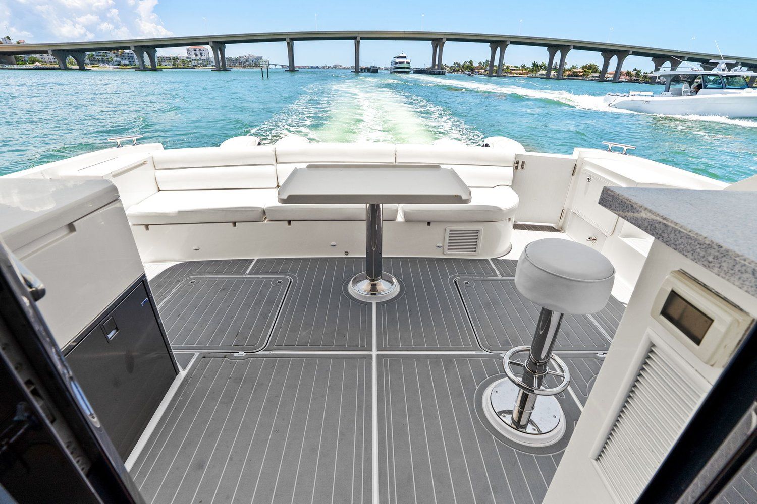 The image shows the stern of a catamaran with seating area and table on the water.