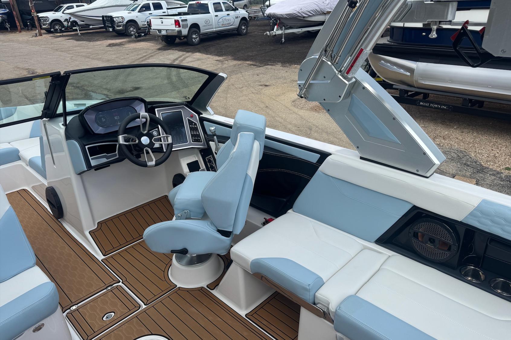 2023 MasterCraft XT24 boat interior with modern helm, blue seating, and wood-style flooring.