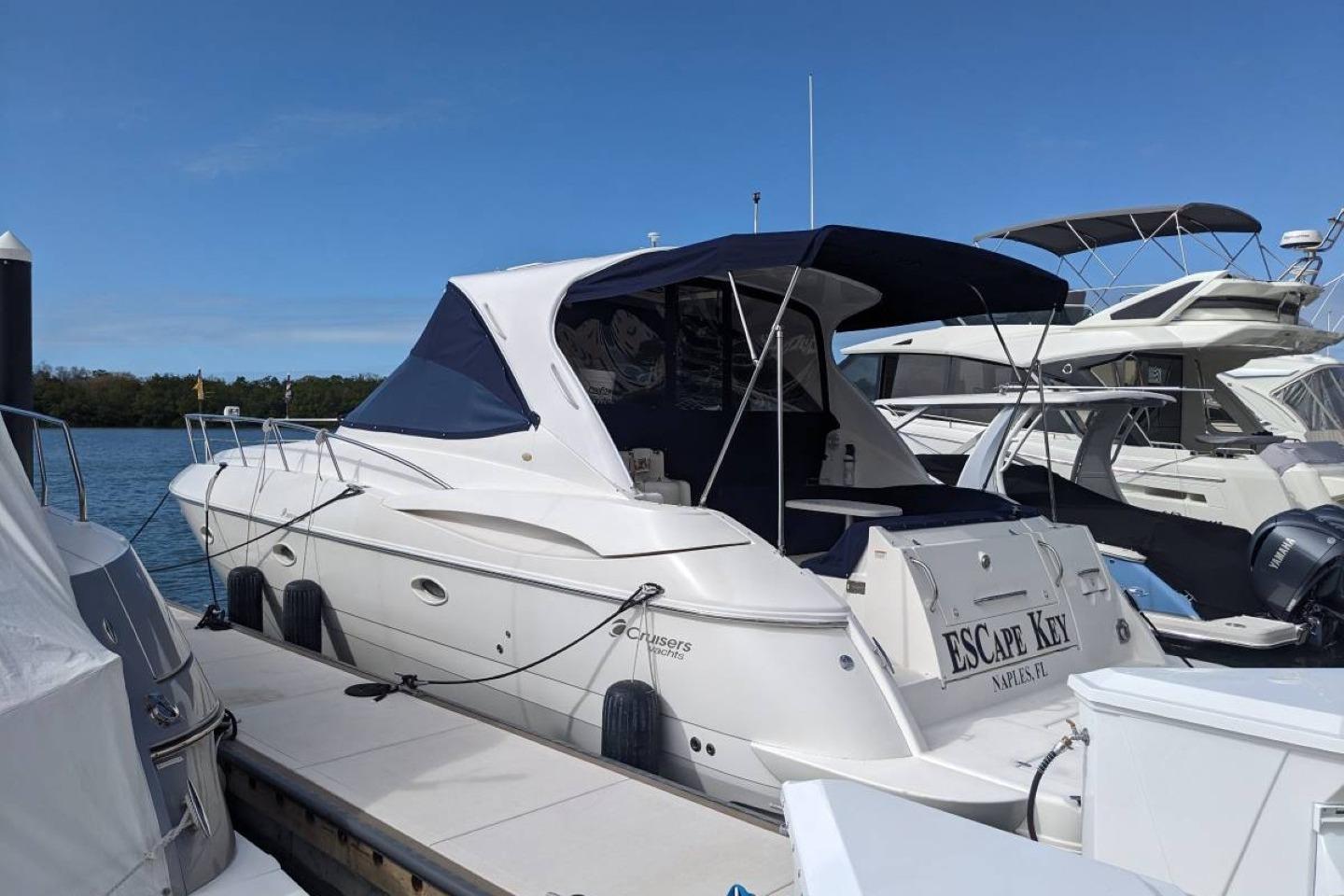 2003 Cruisers 3970 yacht docked at marina, featuring sleek design and blue canopy.