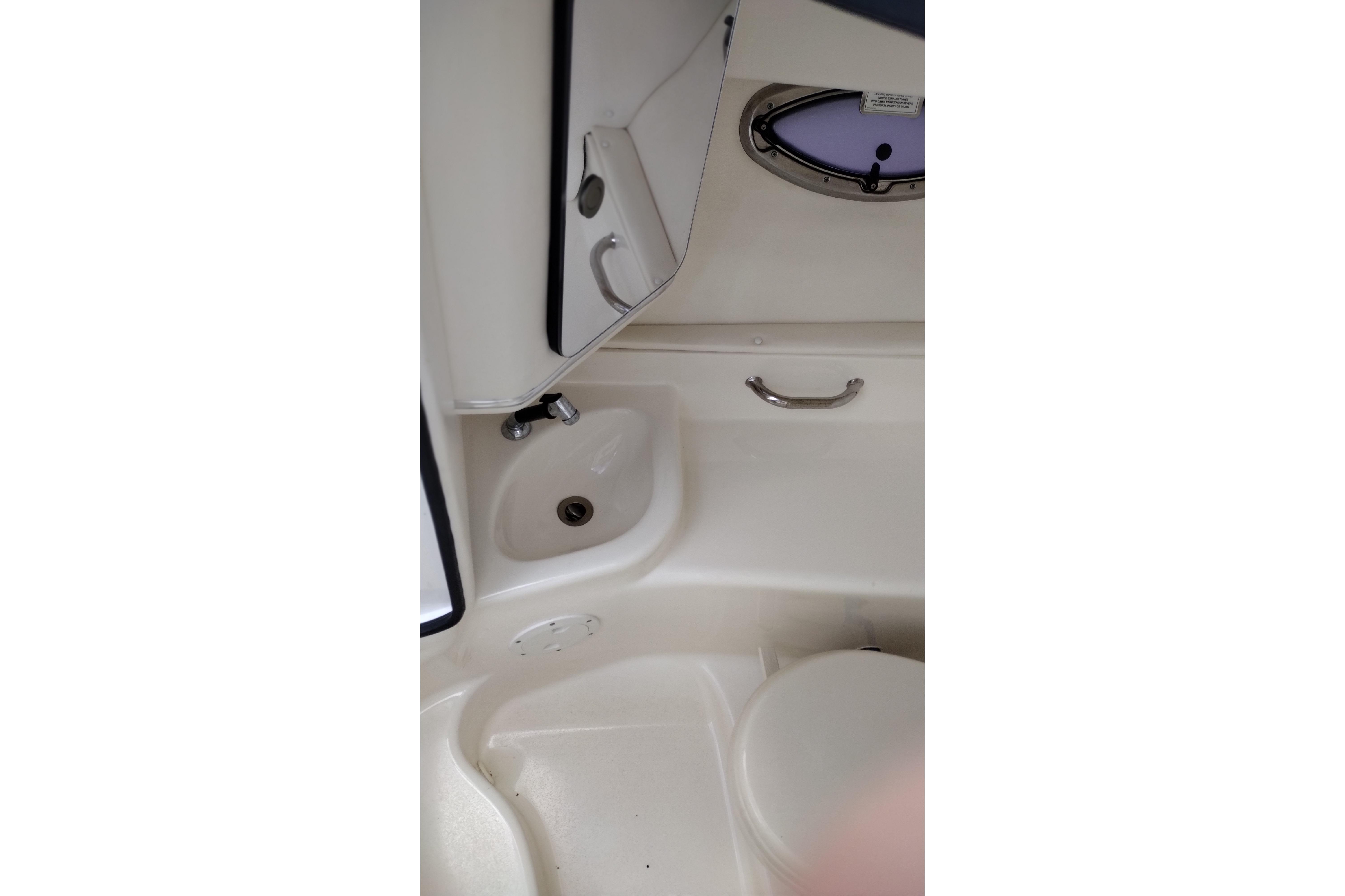 Interior of 2013 Sea Ray 300 SLX boat showing compact bathroom with sink and toilet.