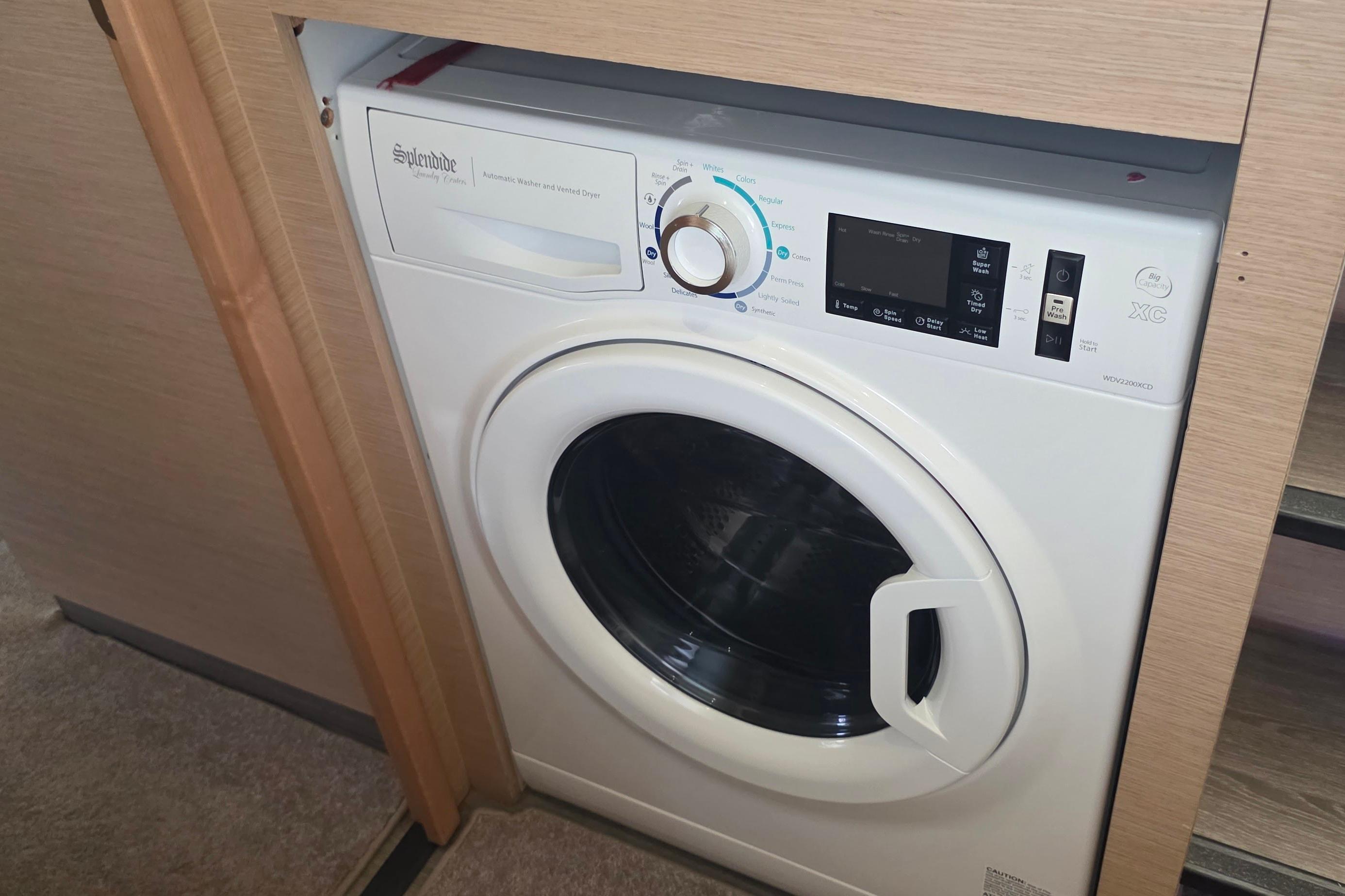 Built-in washing machine on 2018 Fountaine Pajot Motor Yacht 44, neatly integrated in wooden cabinetry.