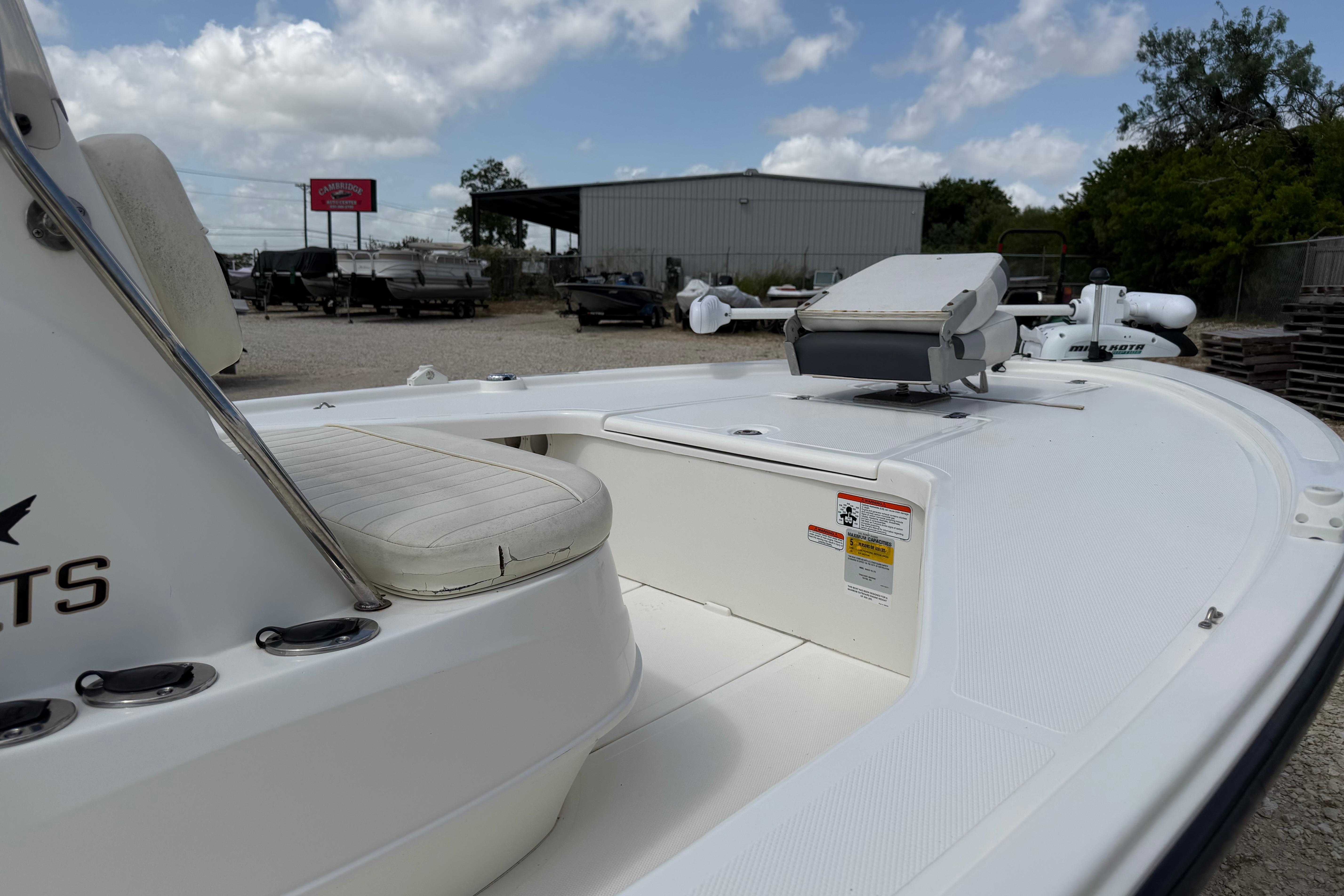 2012 Mako 18 LTS boat interior with seating and storage, parked outdoors under cloudy sky.