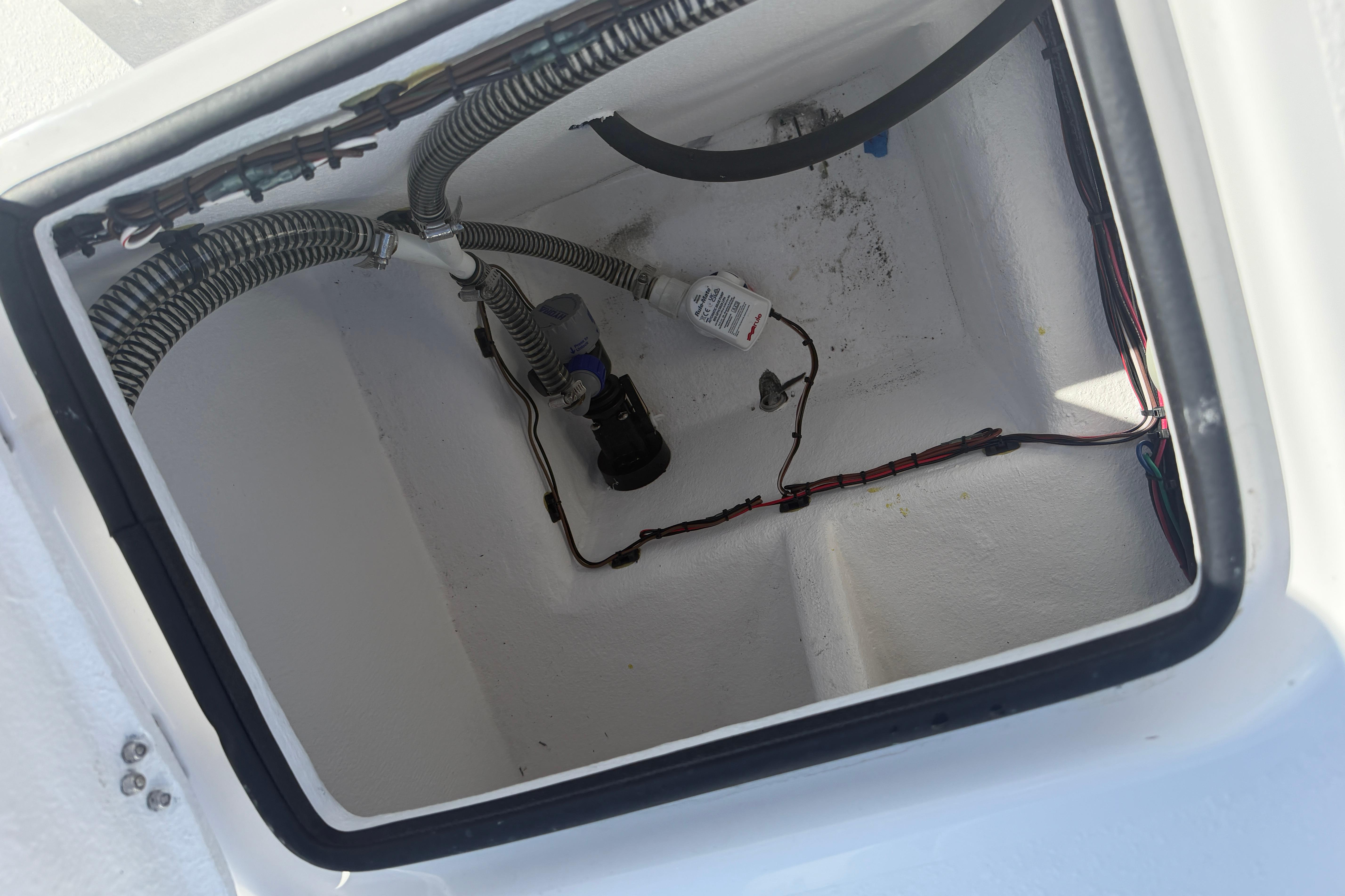 Open compartment of 2026 Skuta 24 Cat boat showing wiring and components.