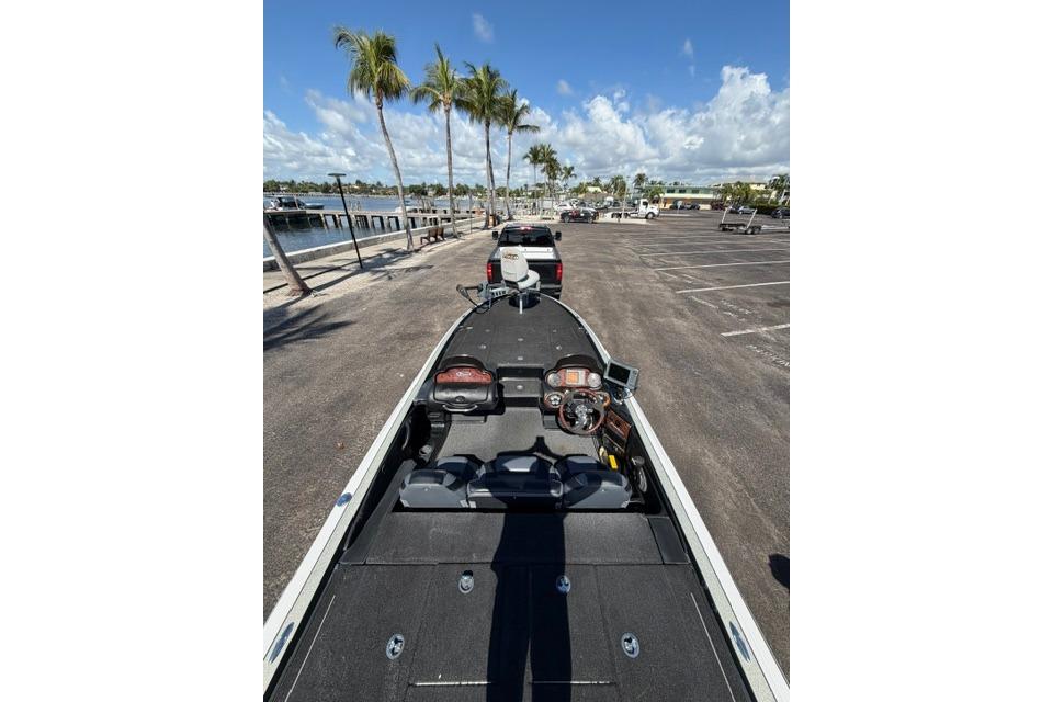 2005 Triton Tr-21X PD boat on trailer, parked near palm trees and waterfront.