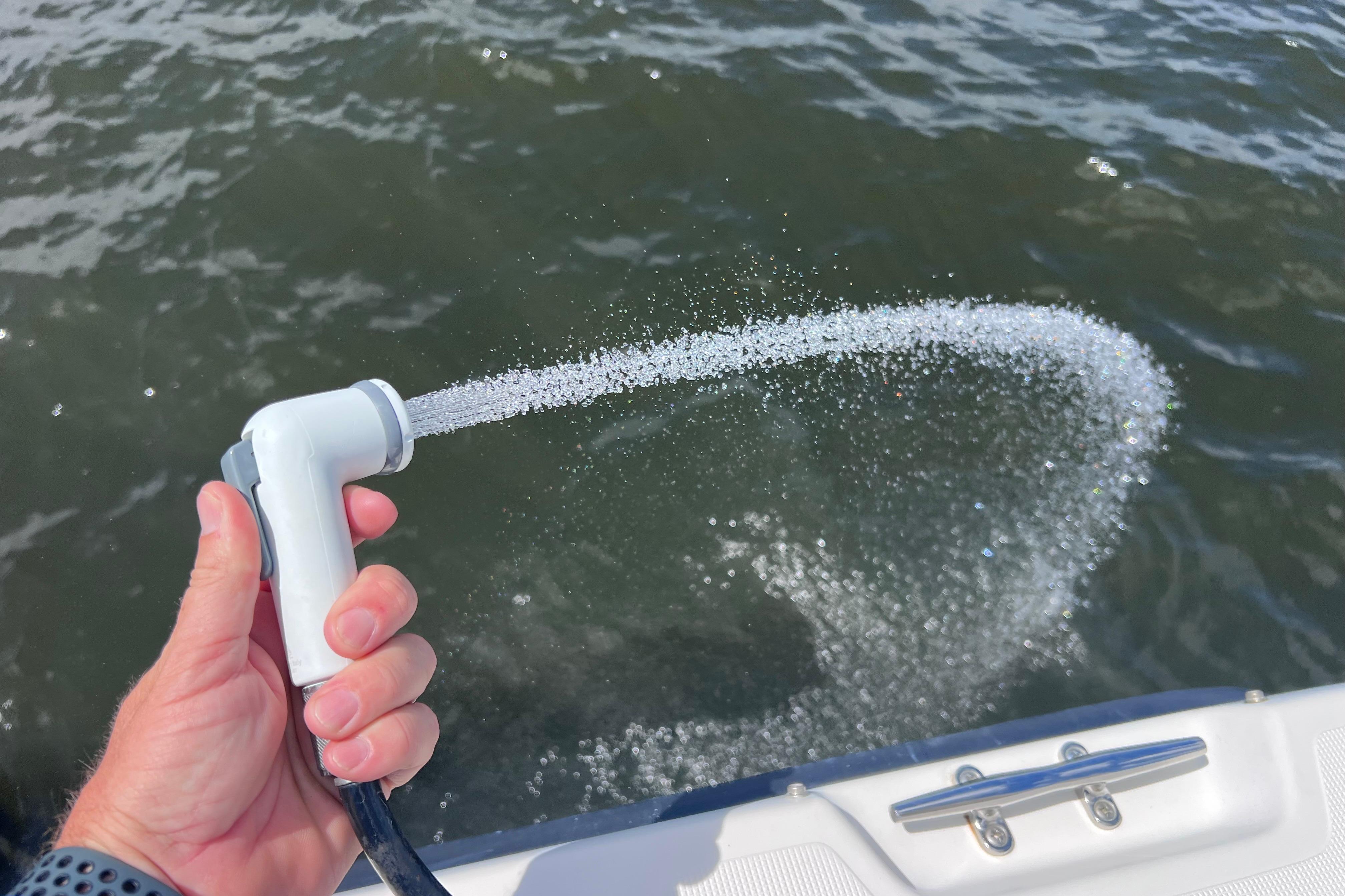 Hand holding a boat hose spraying water, Pursuit 2870 Walkaround, 2004 model.