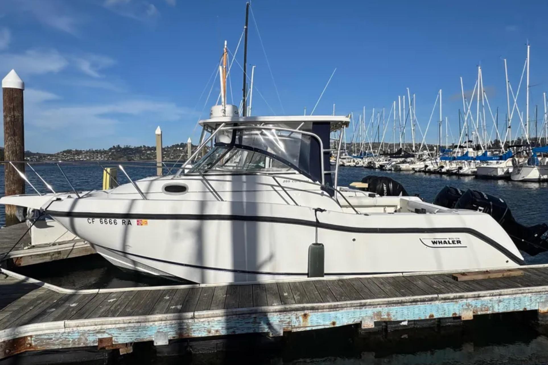 2004 Boston Whaler 255 Conquest docked at marina, clear blue sky background.