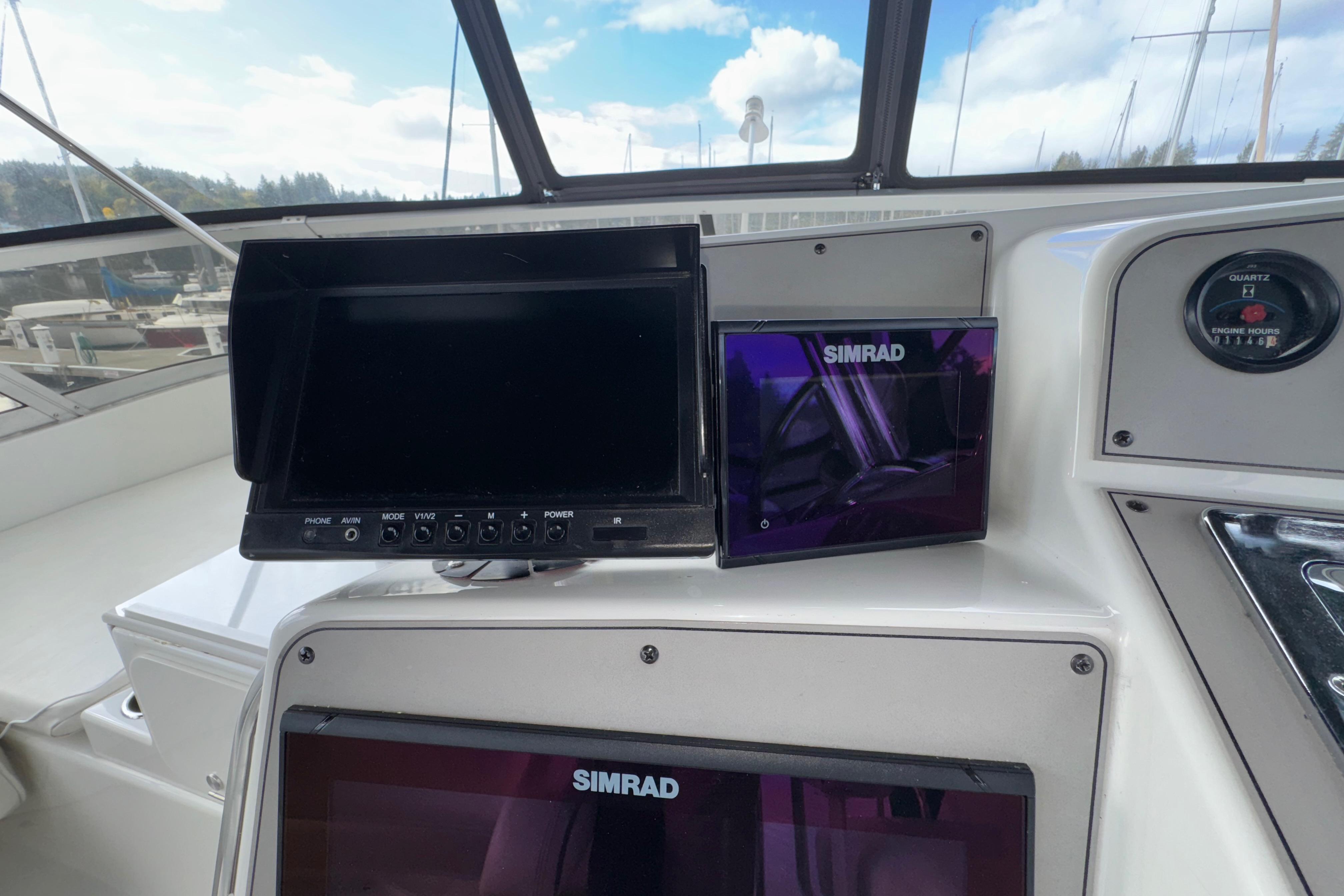 1996 Carver 370 Voyager helm with Simrad navigation displays and engine hour gauge.