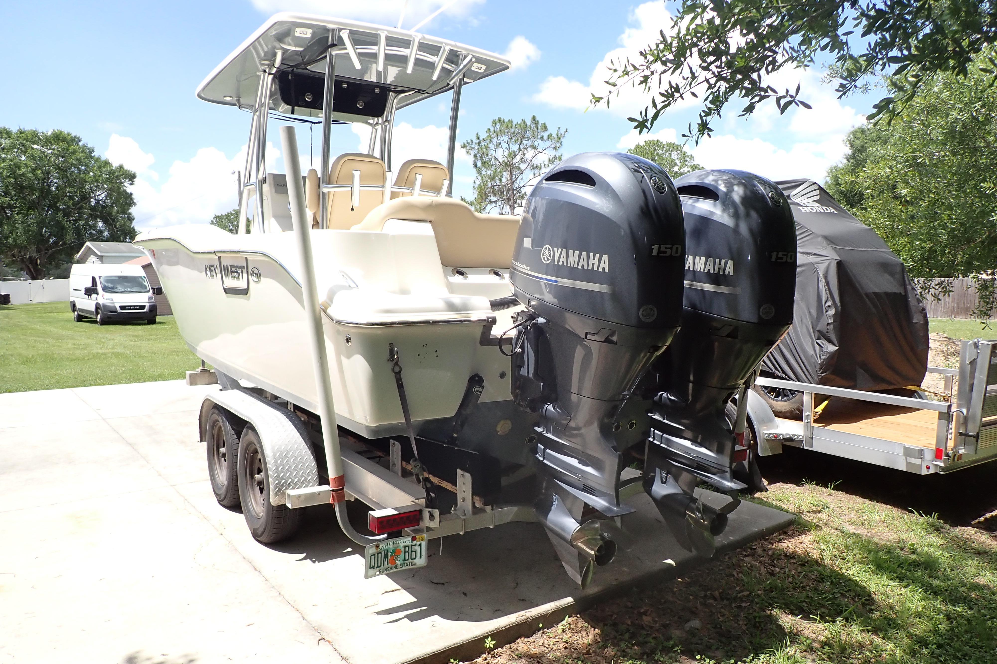 2019 Key West 263 FS boat with dual Yamaha engines on a trailer in a sunny yard.
